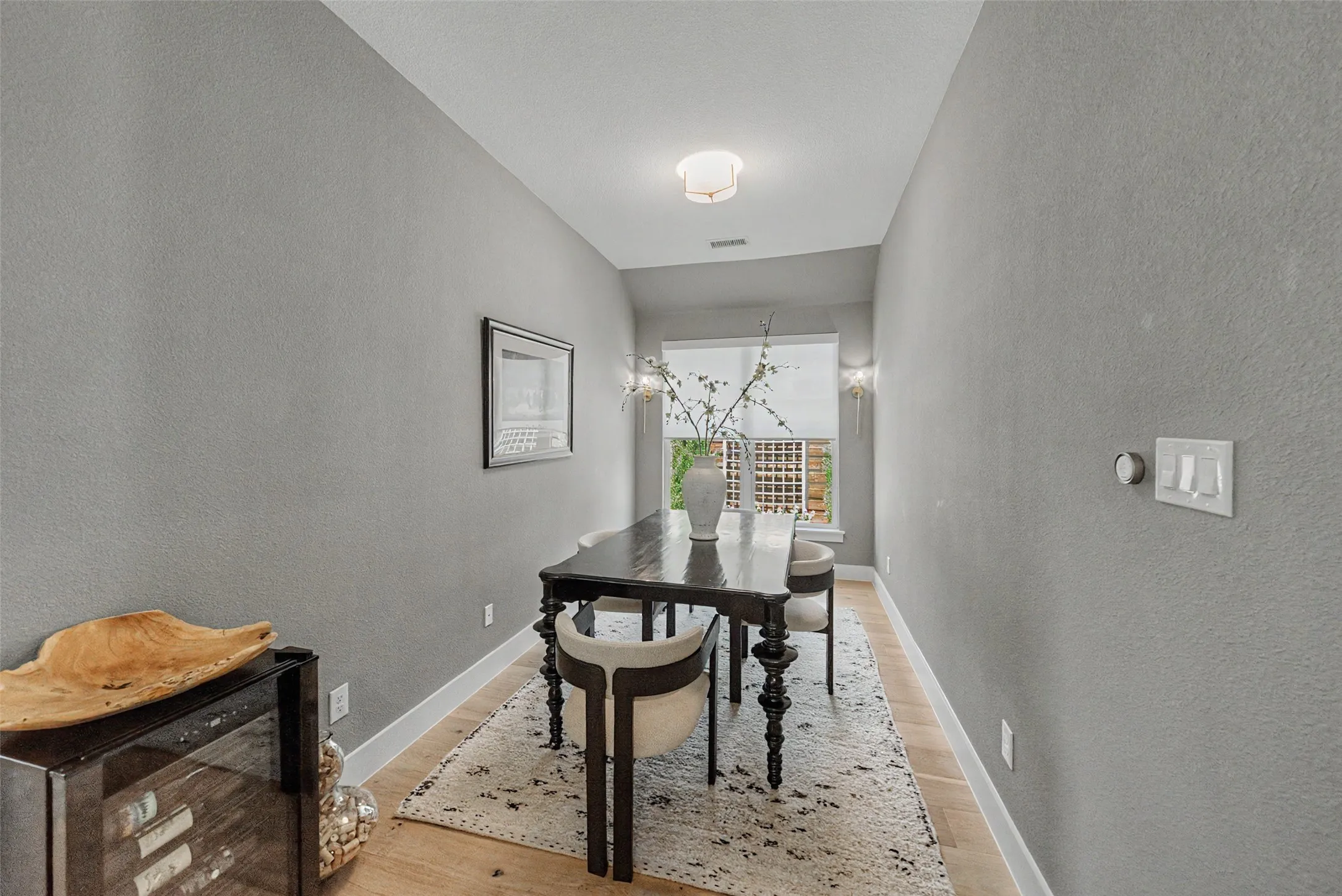Dining area featuring light wood-finish flooring, light grey wall paint, and a built-in beverage cooler