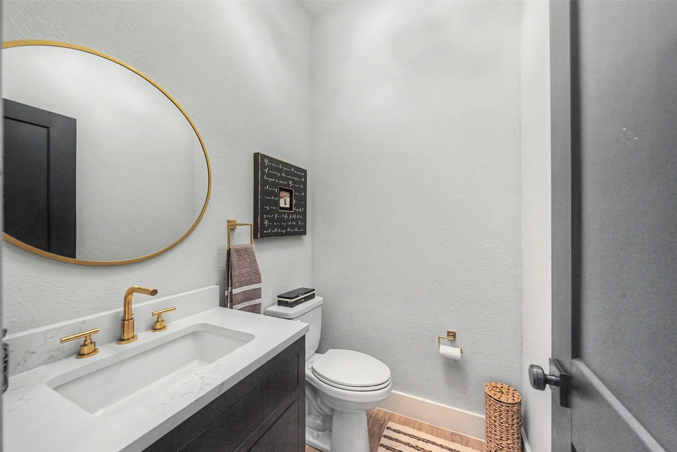 Vanity with integrated rectangular sink and gold-tone faucet set, complemented by a round framed mirror