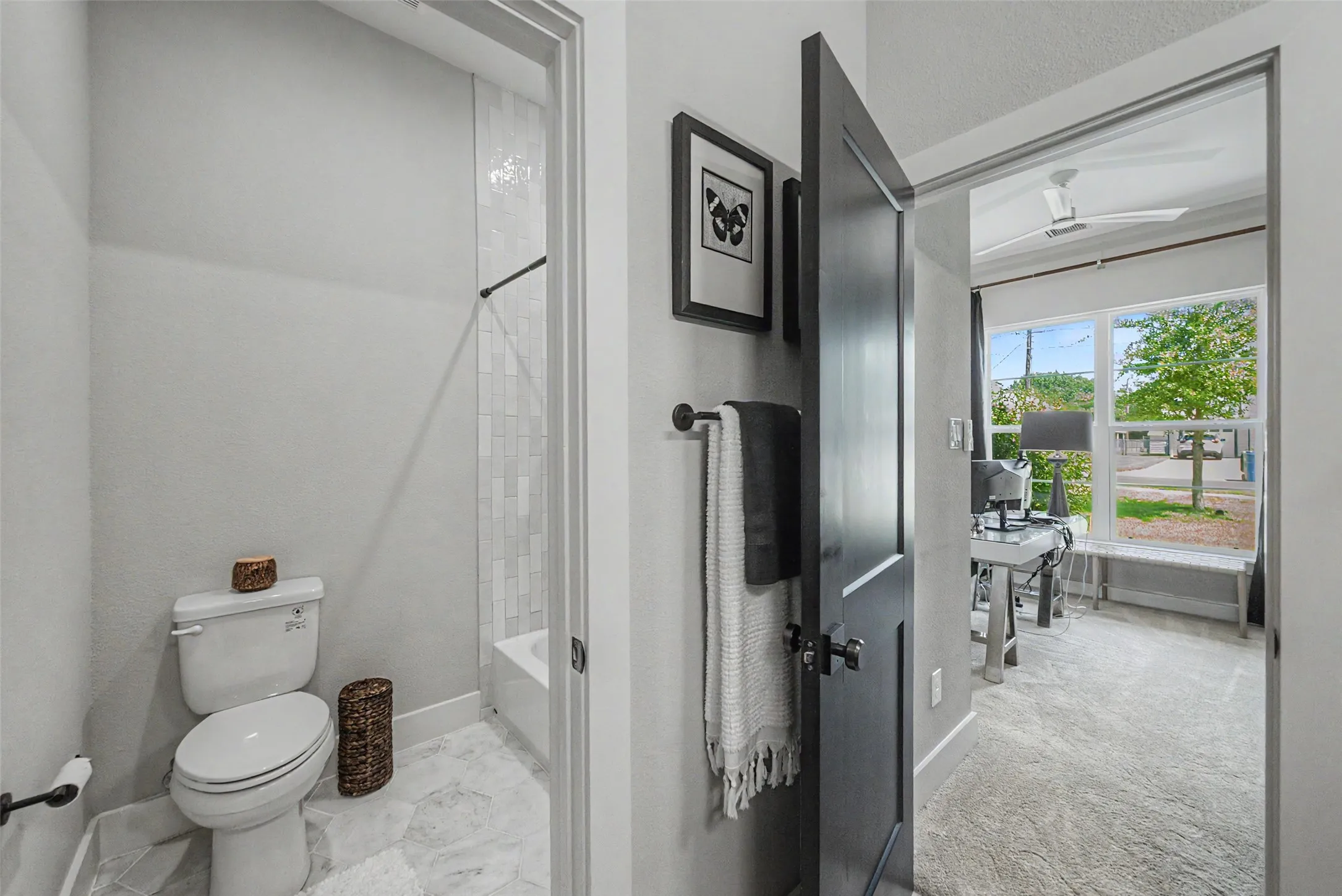 Bathroom featuring a white toilet, light-toned tiled flooring, and a shower with vertical subway tiling