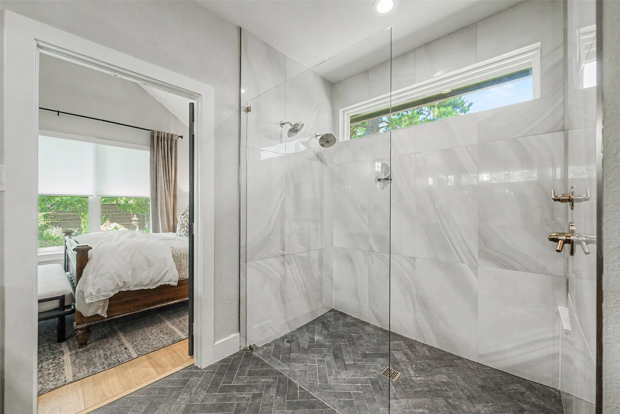 Spacious shower enclosure with floor-to-ceiling glass paneling, dual showerheads, and a transom window