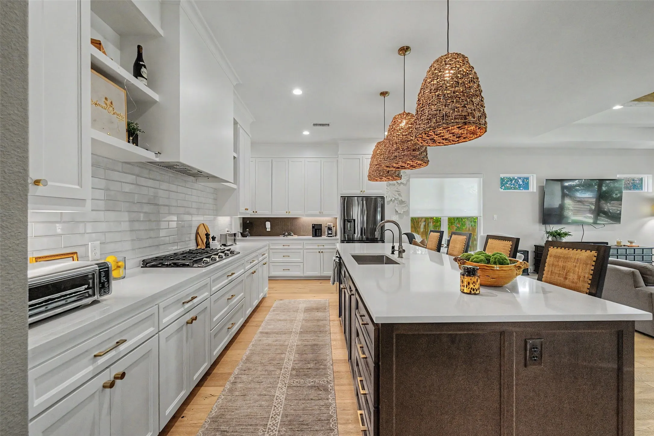 Gourmet kitchen featuring a large central island with seating, white shaker cabinetry, light-toned countertops, a gas range with a tile backsplash, and wood-finish flooring