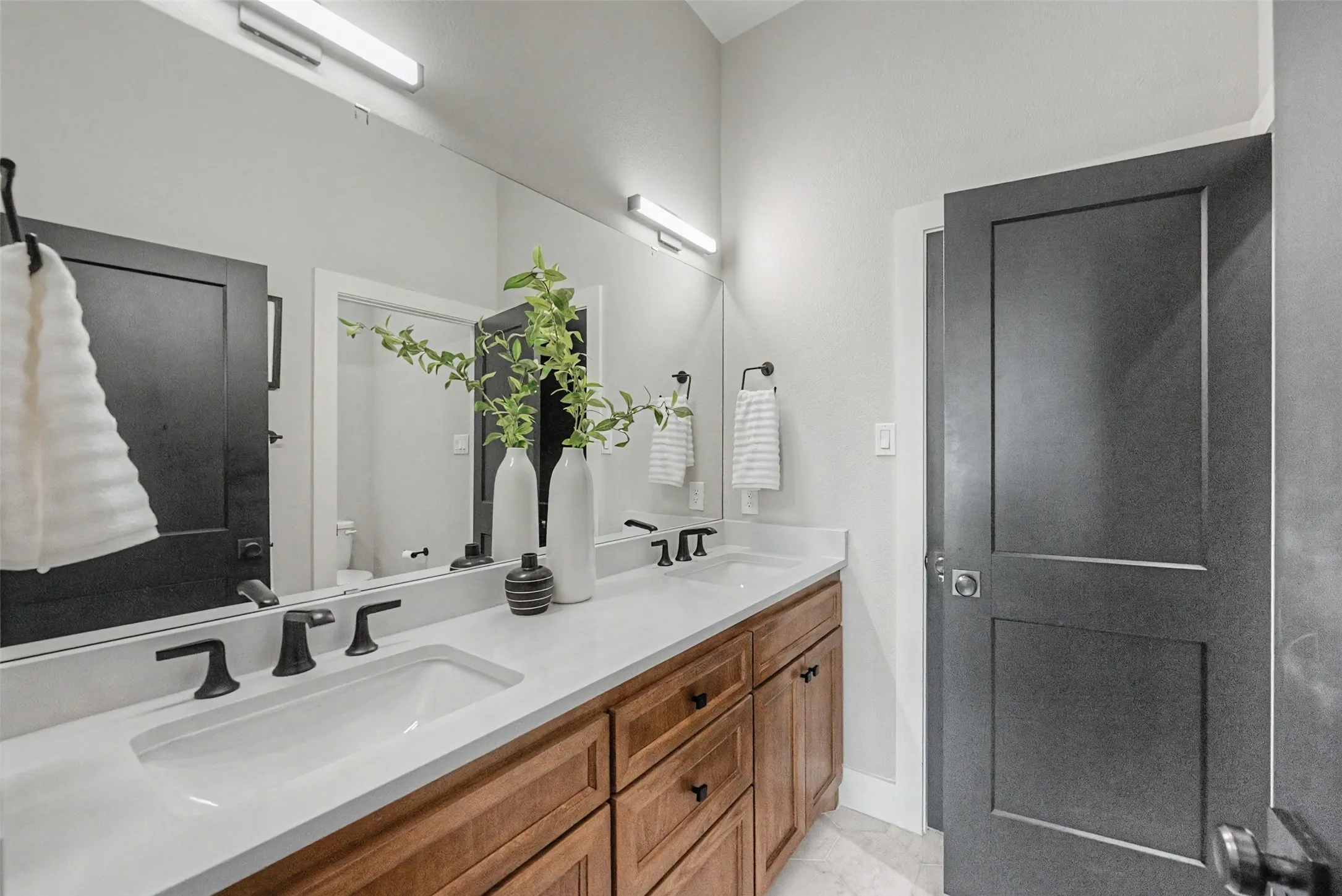 Dual vanity with a white countertop and integrated rectangular sinks, complemented by matte black faucets