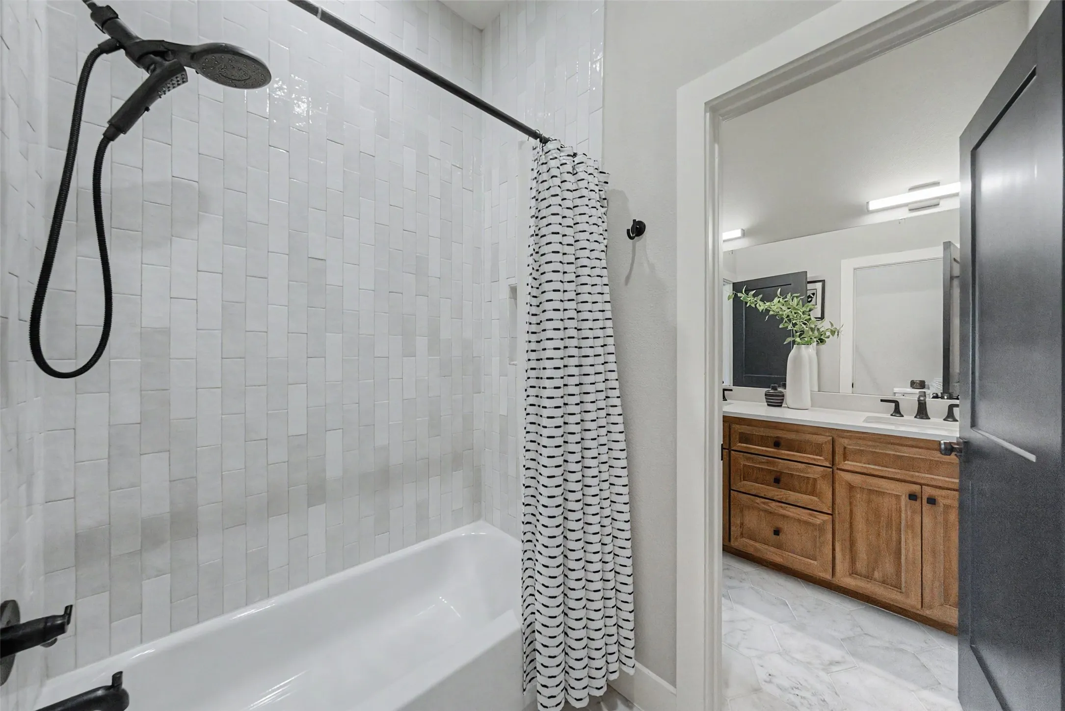 Bathtub with matte black fixtures and vertical subway tile surround