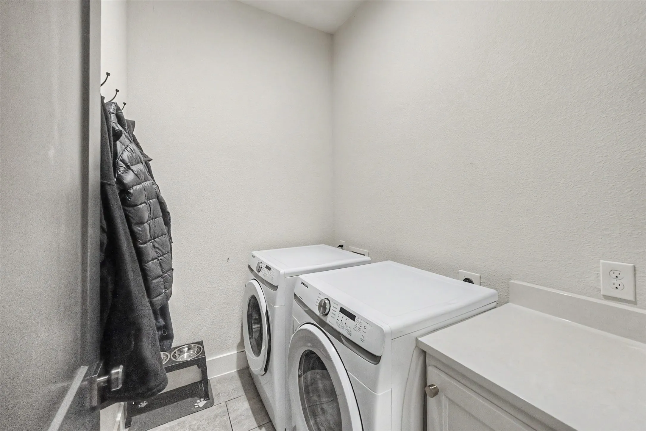 Dedicated laundry area featuring tile flooring, light-toned walls, and a built-in countertop with cabinetry