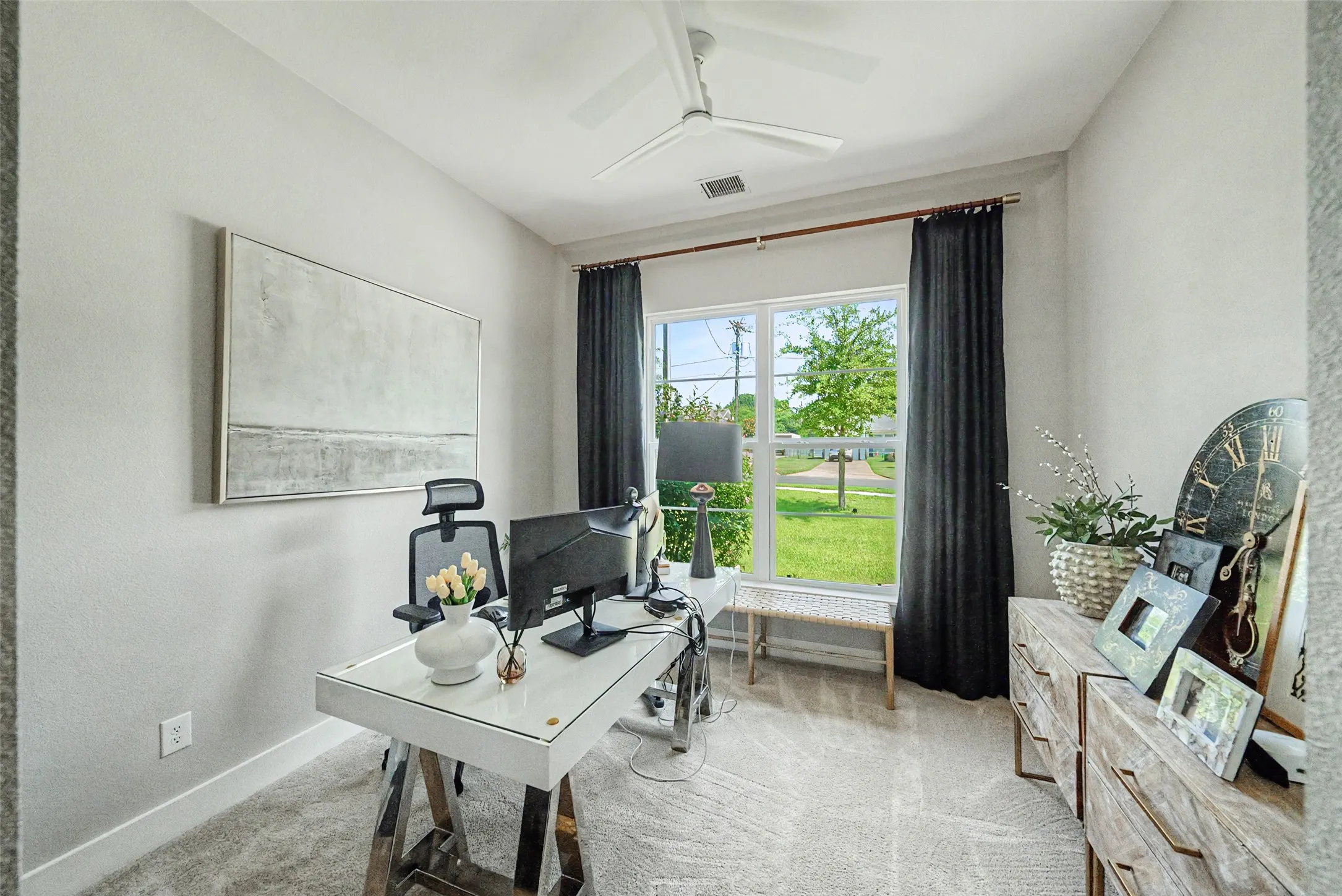 Bright room featuring a large window, ceiling fan, and carpeted flooring