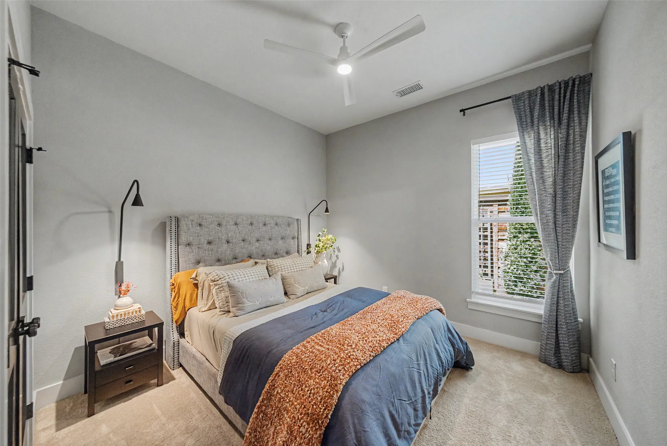 Carpeted bedroom with a single window, a ceiling fan with integrated lighting, and a door featuring black hardware