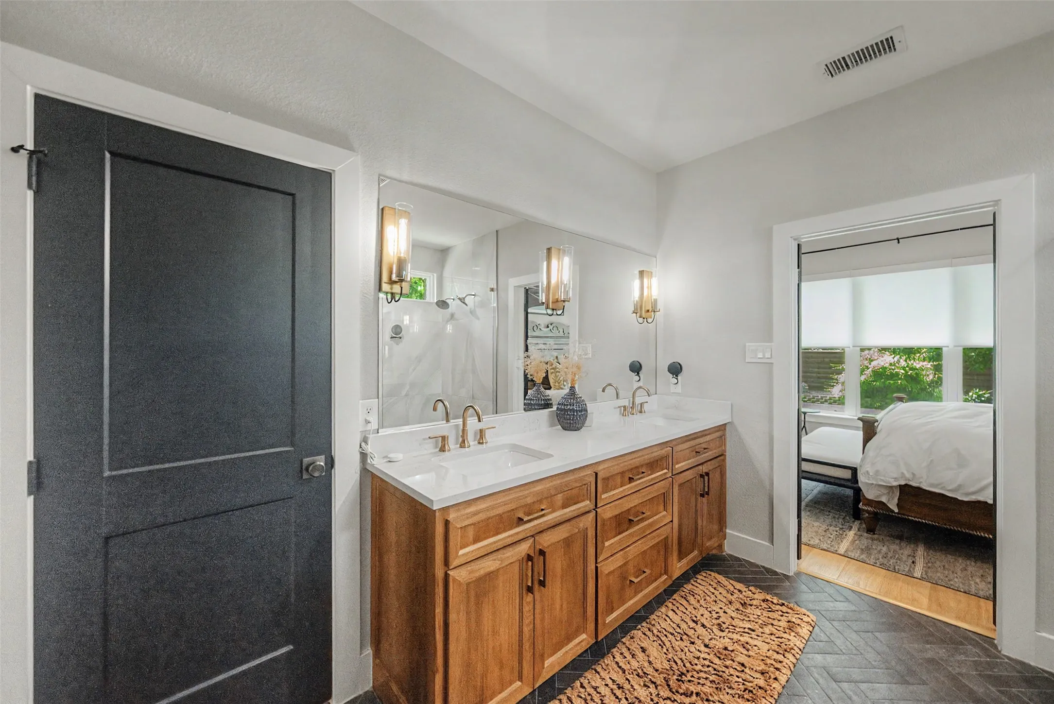 Bathroom vanity featuring a dual sink, wood-finish cabinetry, quartz countertop, and gold-tone fixtures