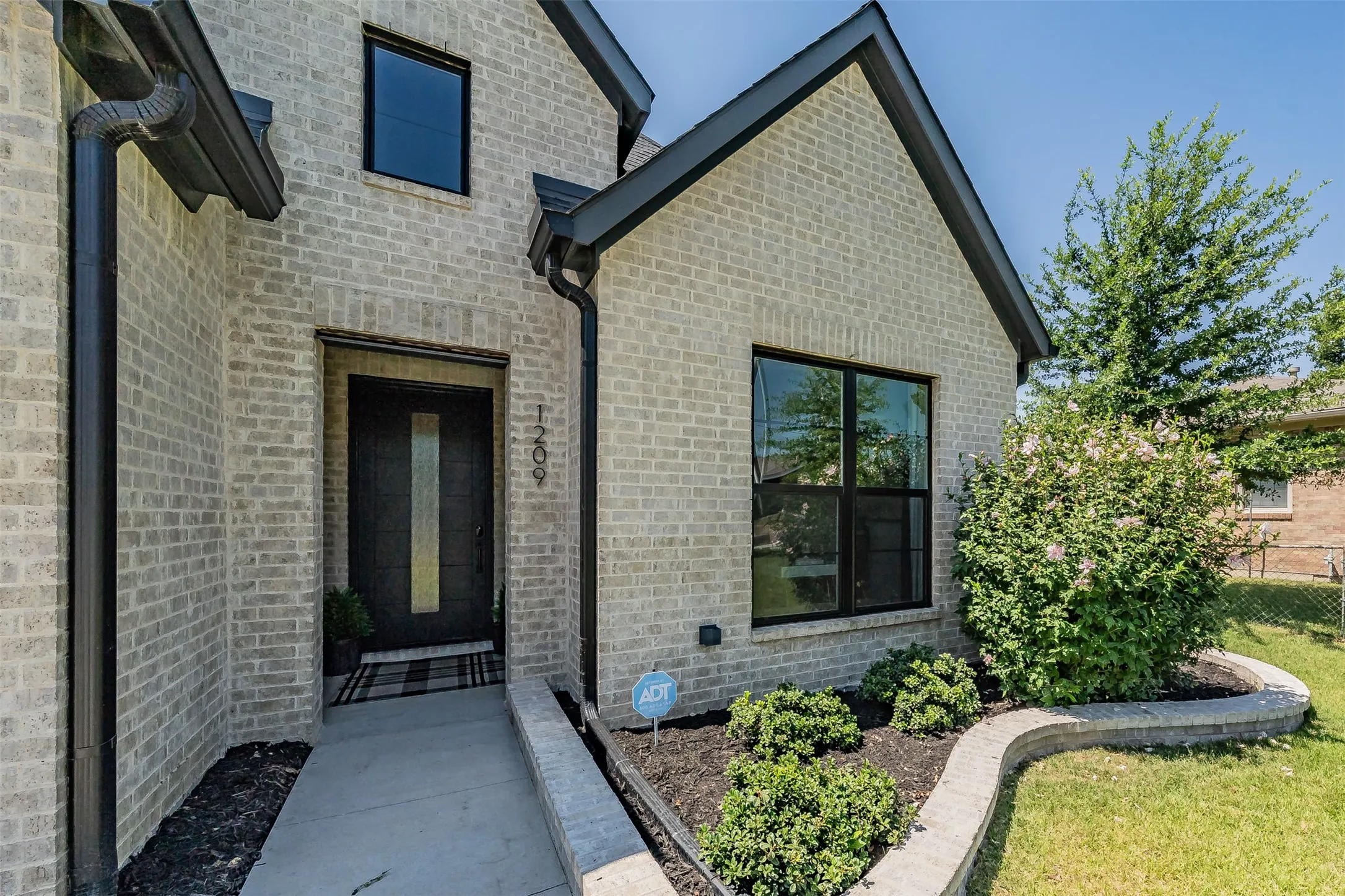 Light-colored brick exterior featuring dark trim and gutters