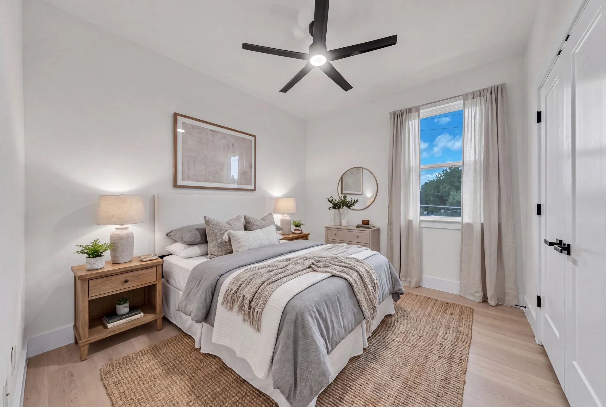Bright bedroom featuring light wood-finish flooring and white baseboards