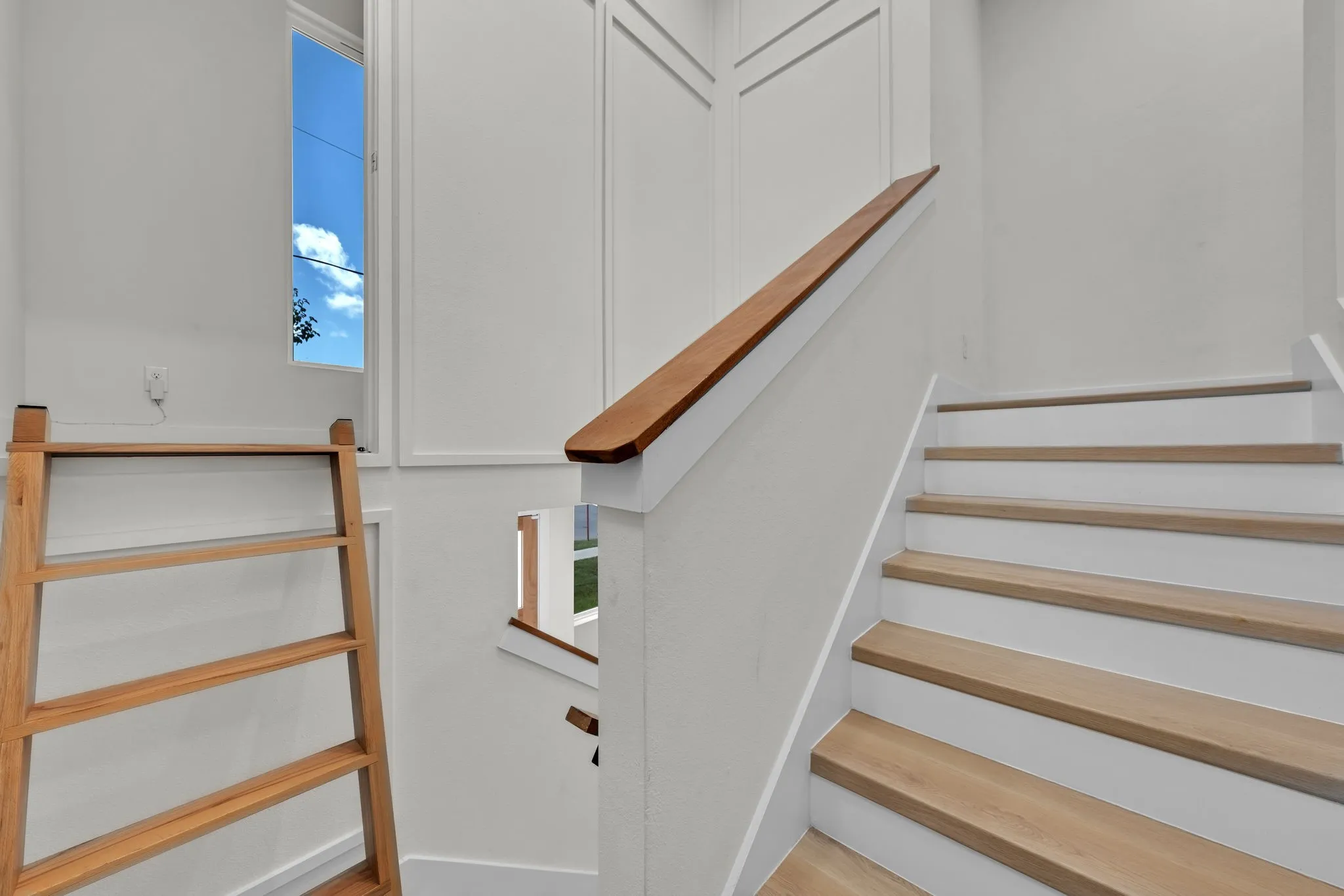 Staircase featuring wood-finish treads and risers, a wood-finish handrail, and wainscoting detailing on the walls