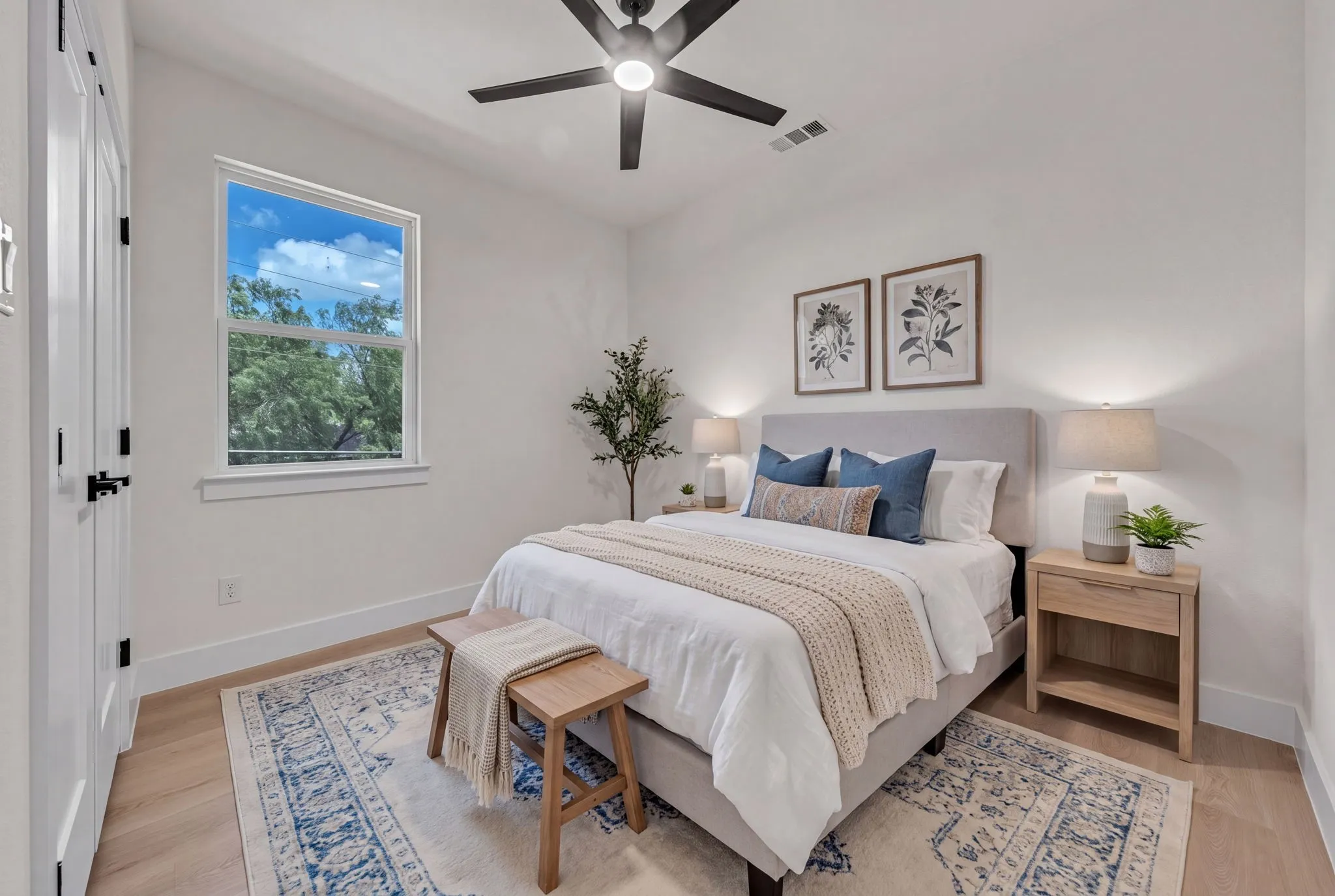 Bedroom featuring light wood-finish flooring, a contemporary ceiling fan, a window with exterior tree views, and white baseboards