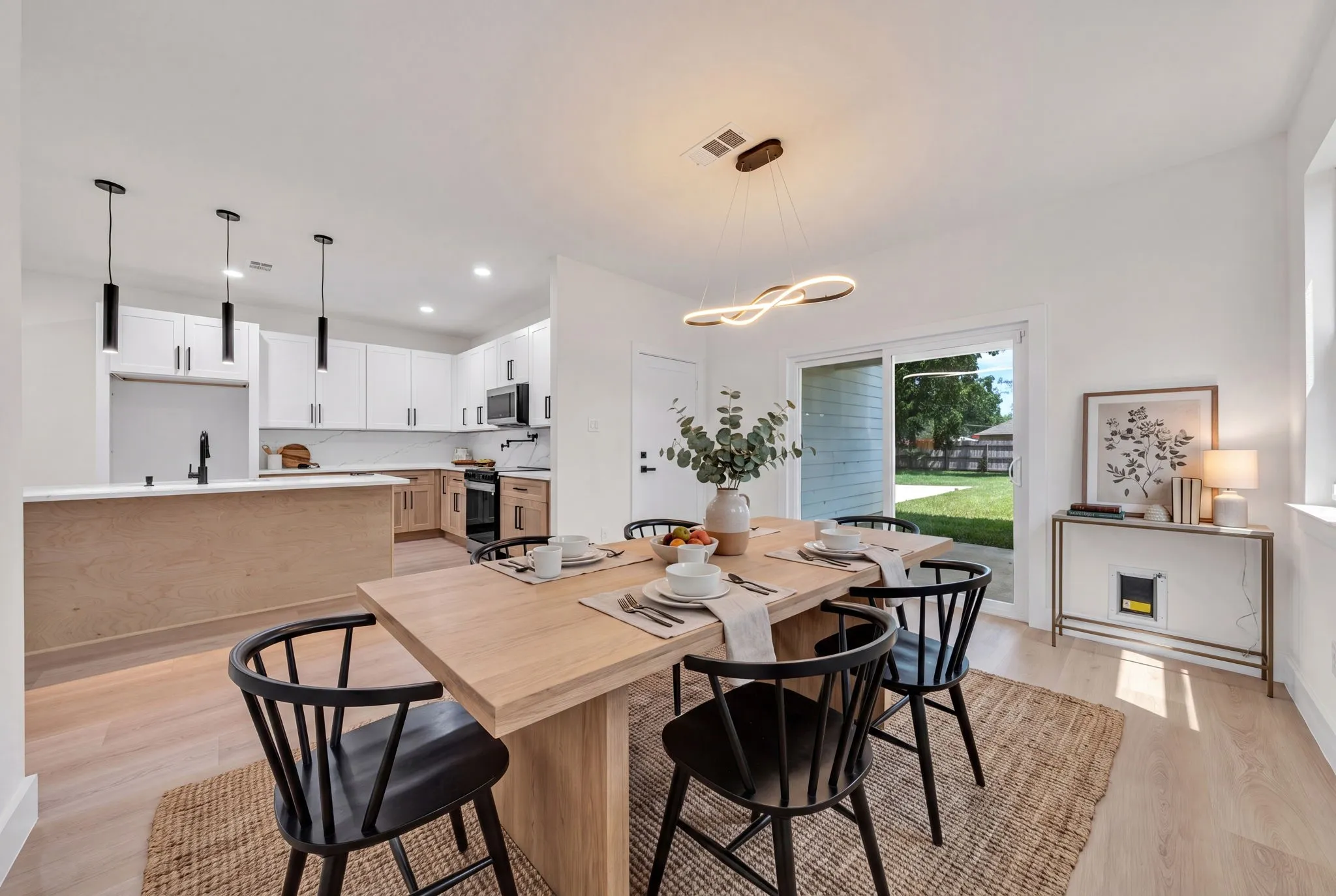 Dining area featuring wood-finish flooring, a contemporary linear chandelier, and a sliding glass door providing access to the backyard