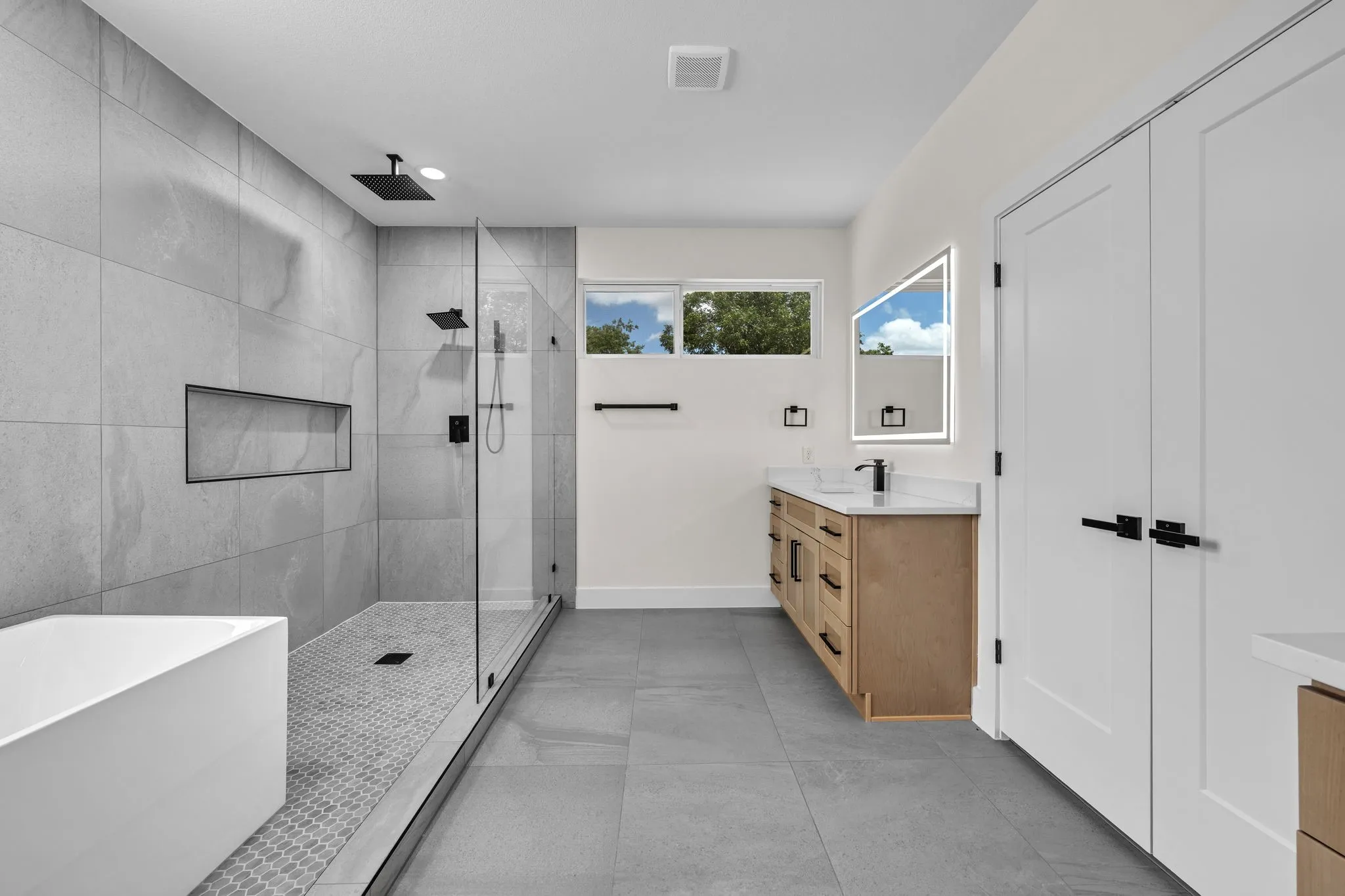 Spacious bathroom featuring a large walk-in shower with a glass enclosure and textured tile flooring