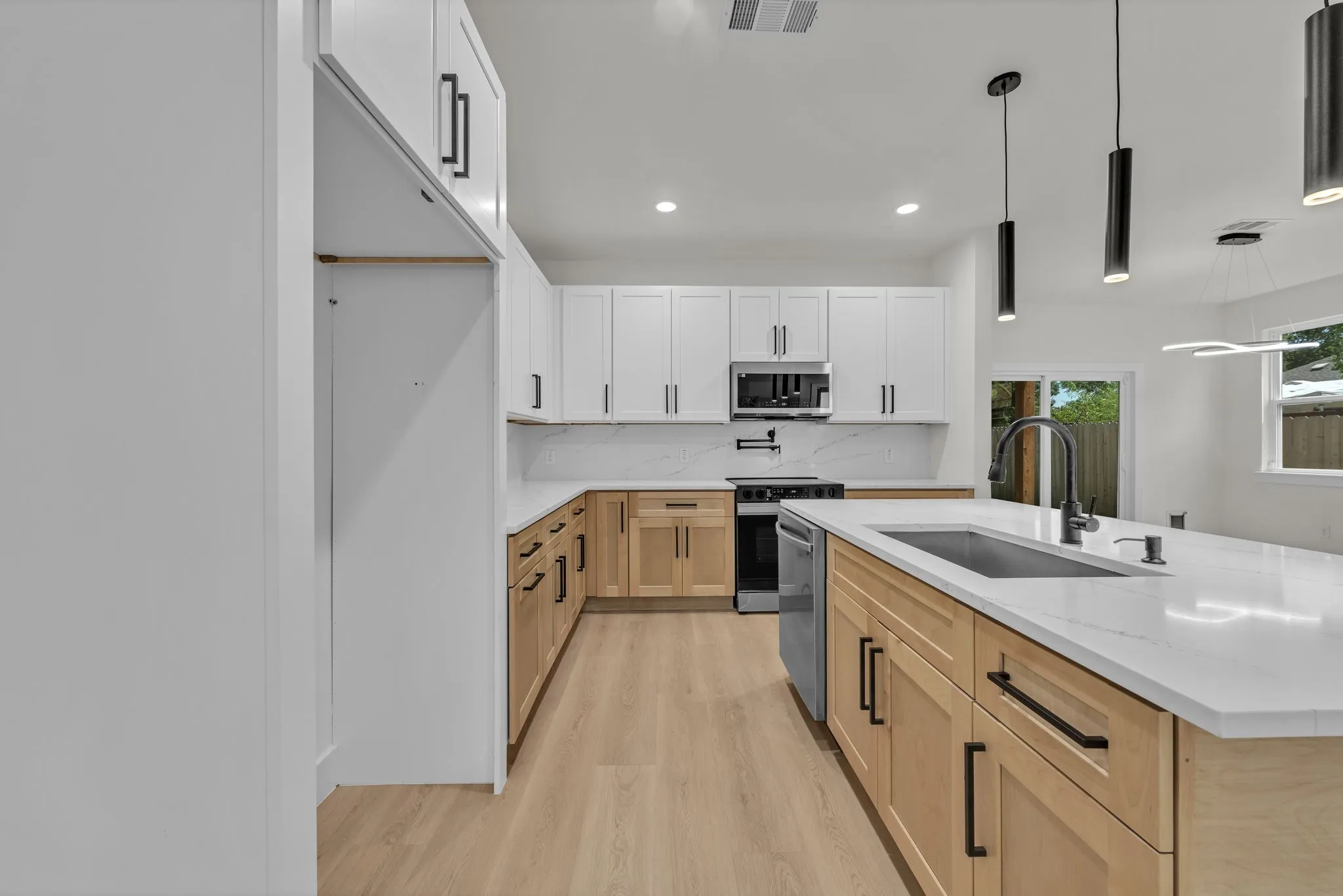 Modern kitchen featuring a large island with an undermount sink, quartz countertops, and two-tone cabinetry