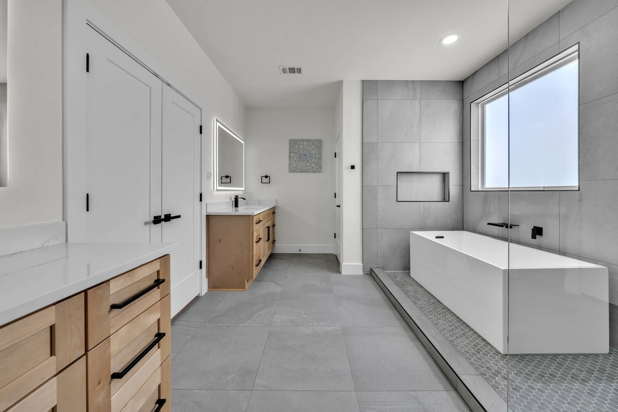Contemporary bathroom featuring a freestanding tub, large format tile walls, and a walk-in shower with mosaic tile flooring