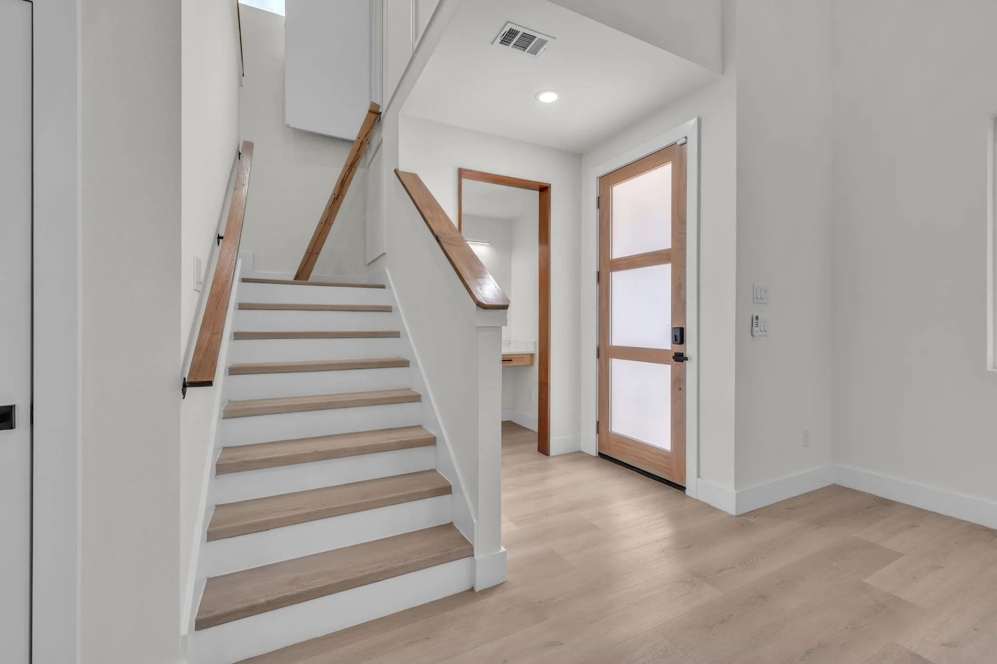 Contemporary interior featuring a wood-finish entry door with frosted panels