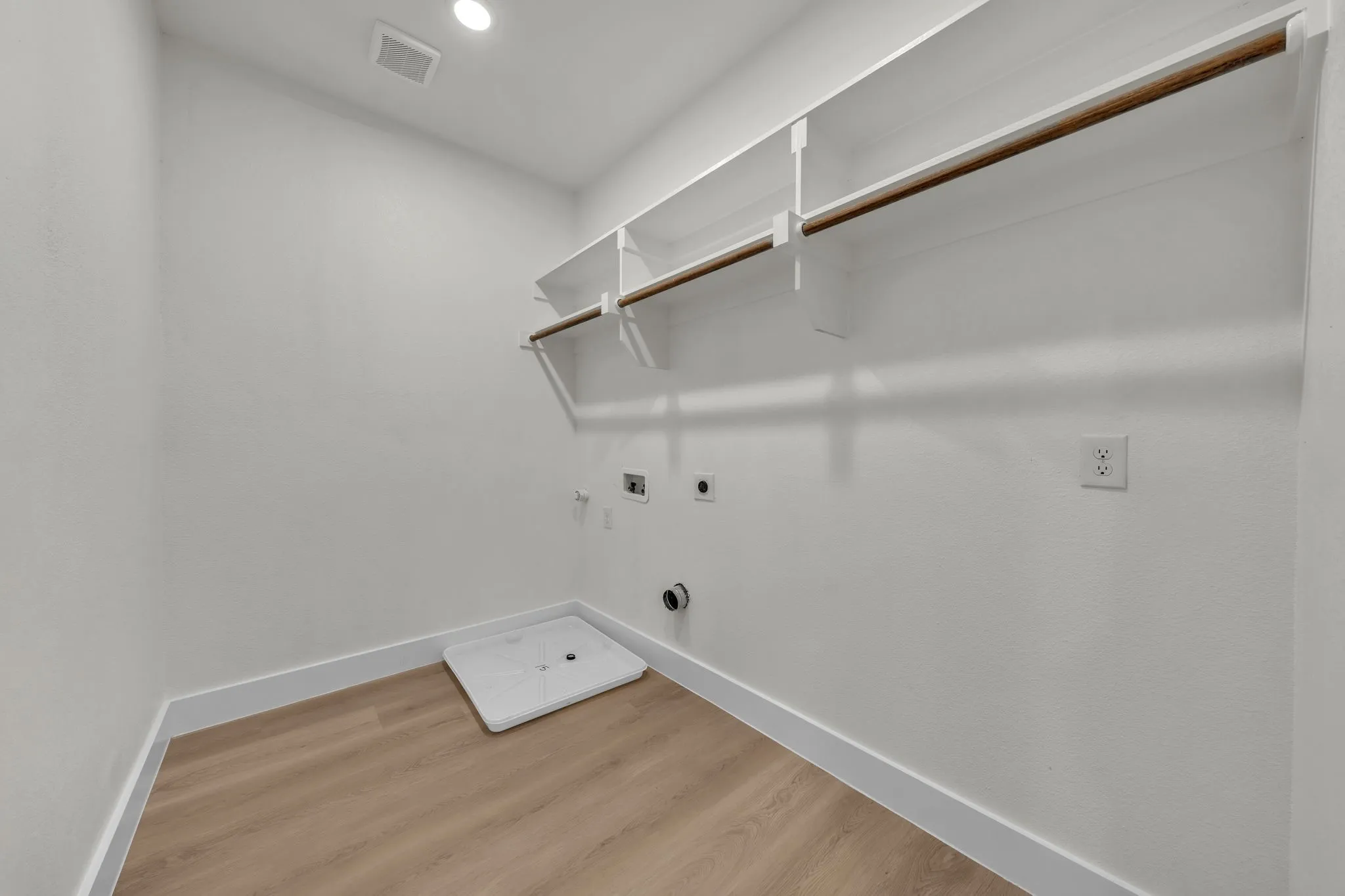 Dedicated utility space featuring wood-finish flooring and bright white walls