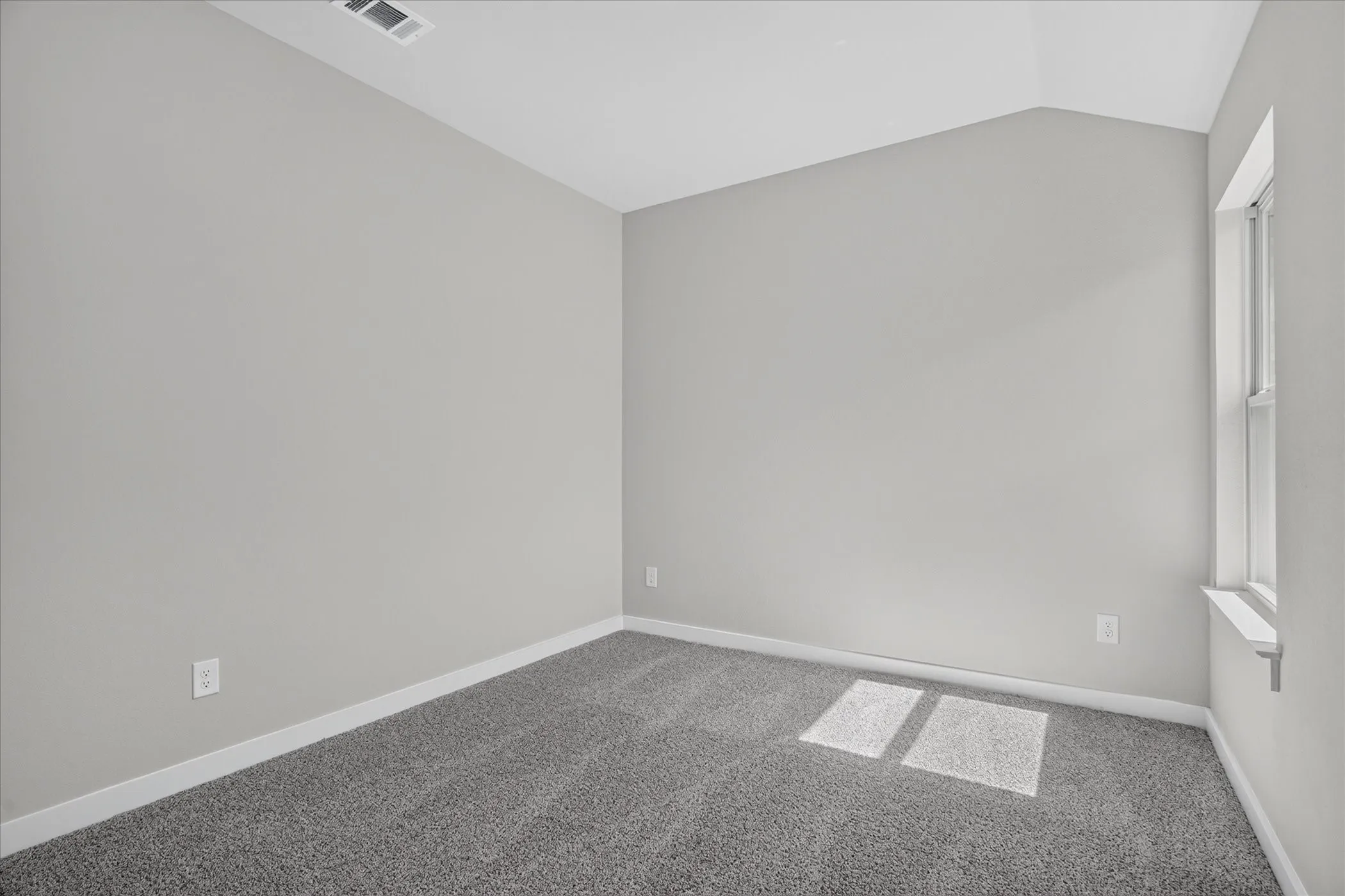 Neutral wall tones with vaulted ceilings and textured carpeting