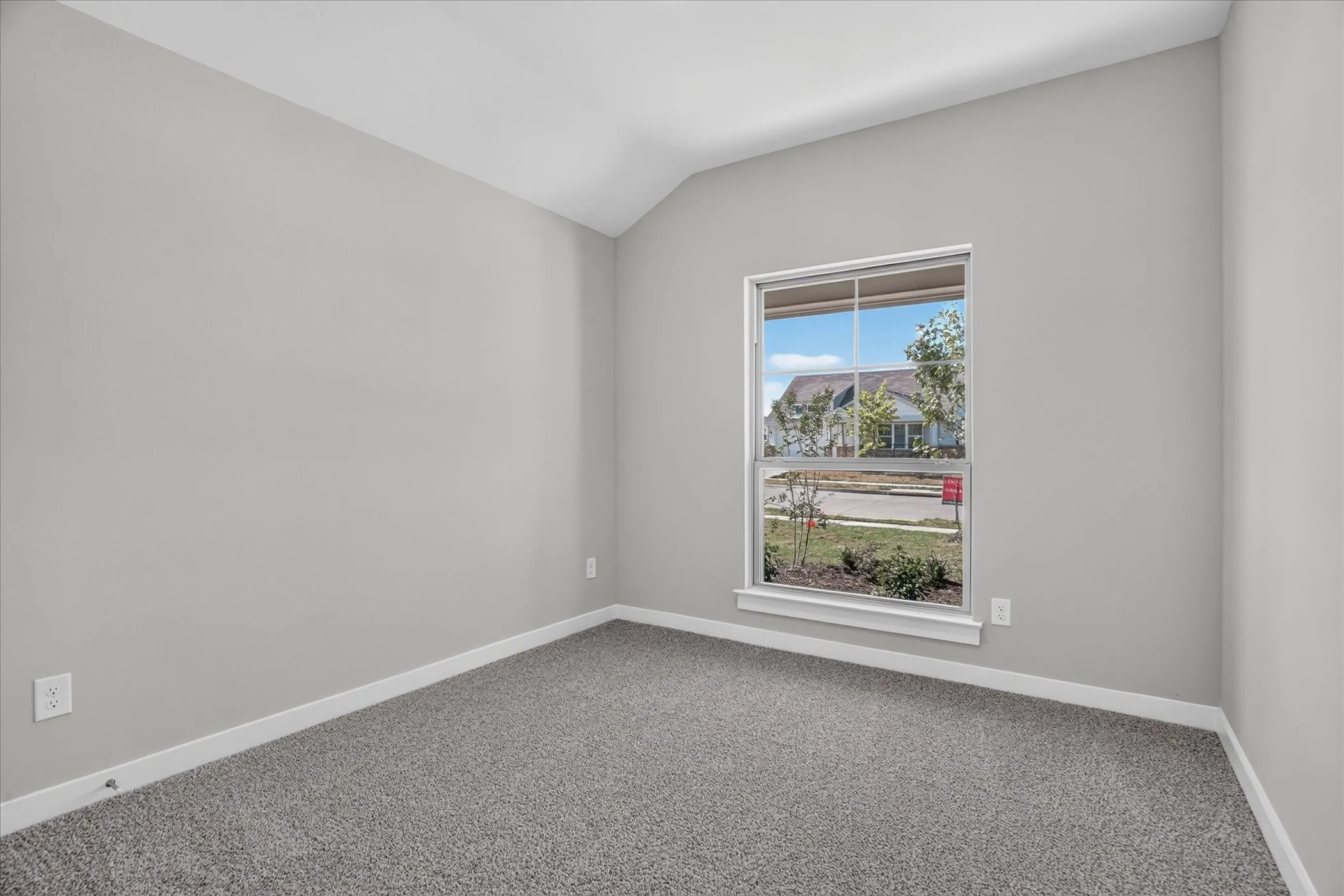 Vaulted ceiling, neutral wall paint, white trim, carpeted flooring, and a large window