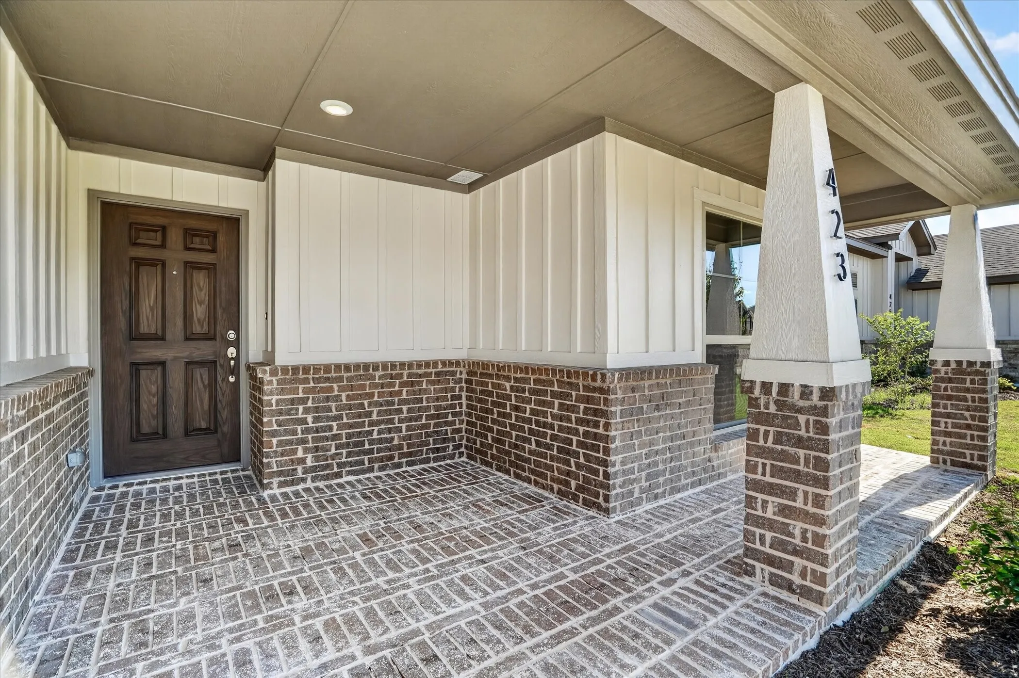Covered front entry featuring brick and vertical siding