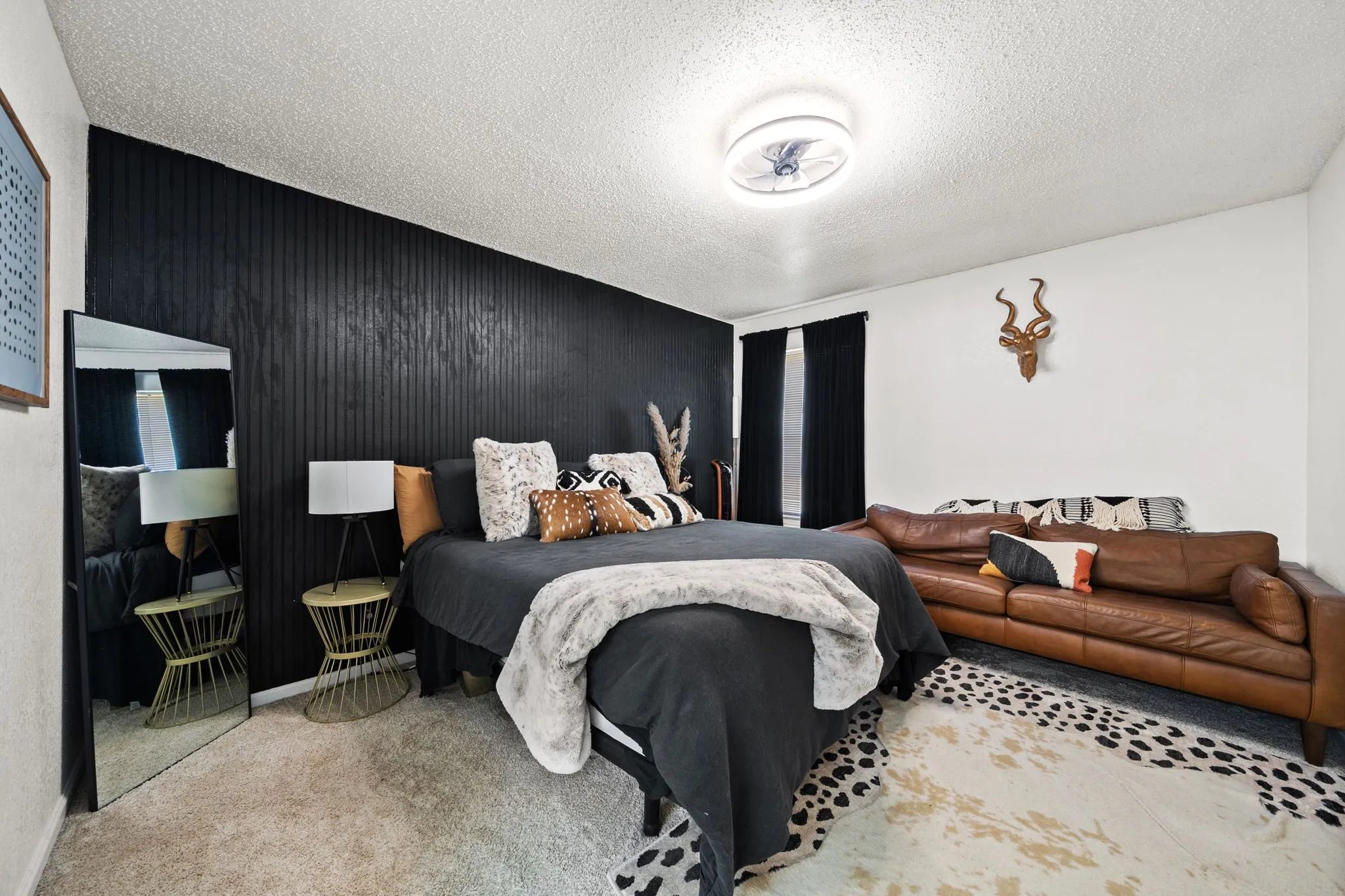 Room featuring a black textured accent wall, light-colored carpet flooring, a ceiling-mounted light fixture, and dark window coverings