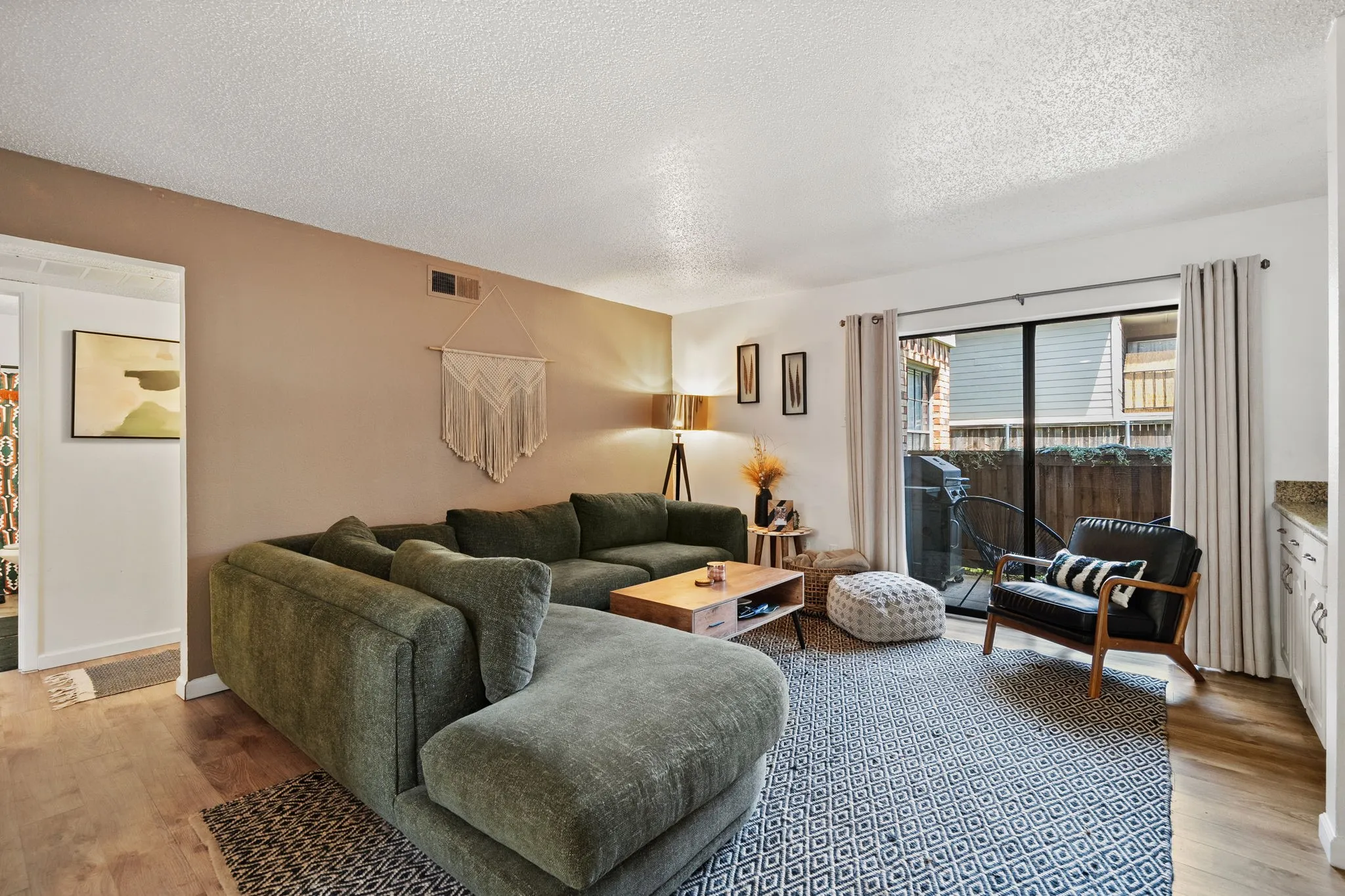 Open concept living space featuring wood-finish flooring, a neutral color palette, and a sliding glass door providing access to an outdoor area