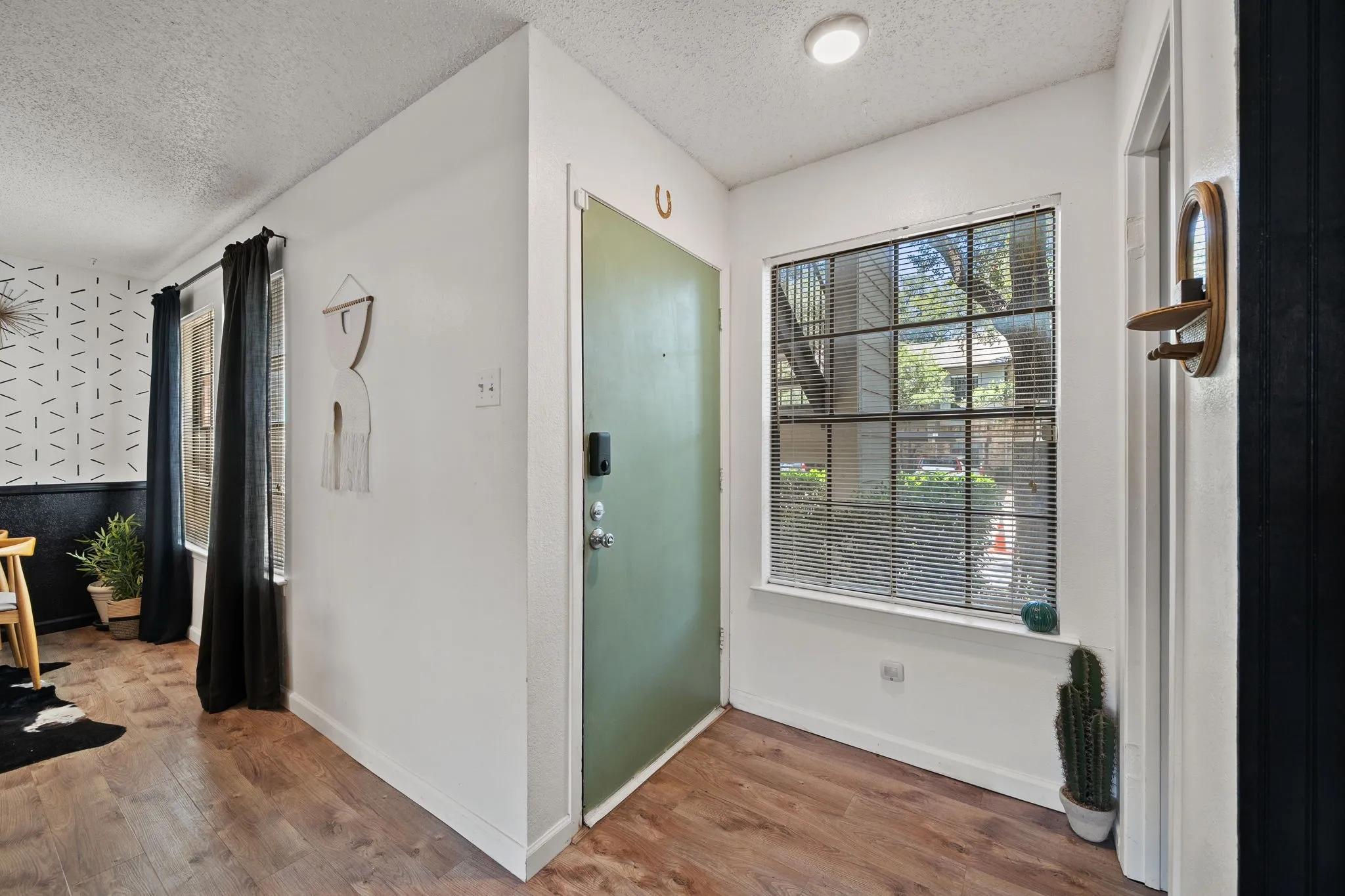 Exterior entry featuring a dark brown door, multiple windows with blinds, and an exterior light fixture