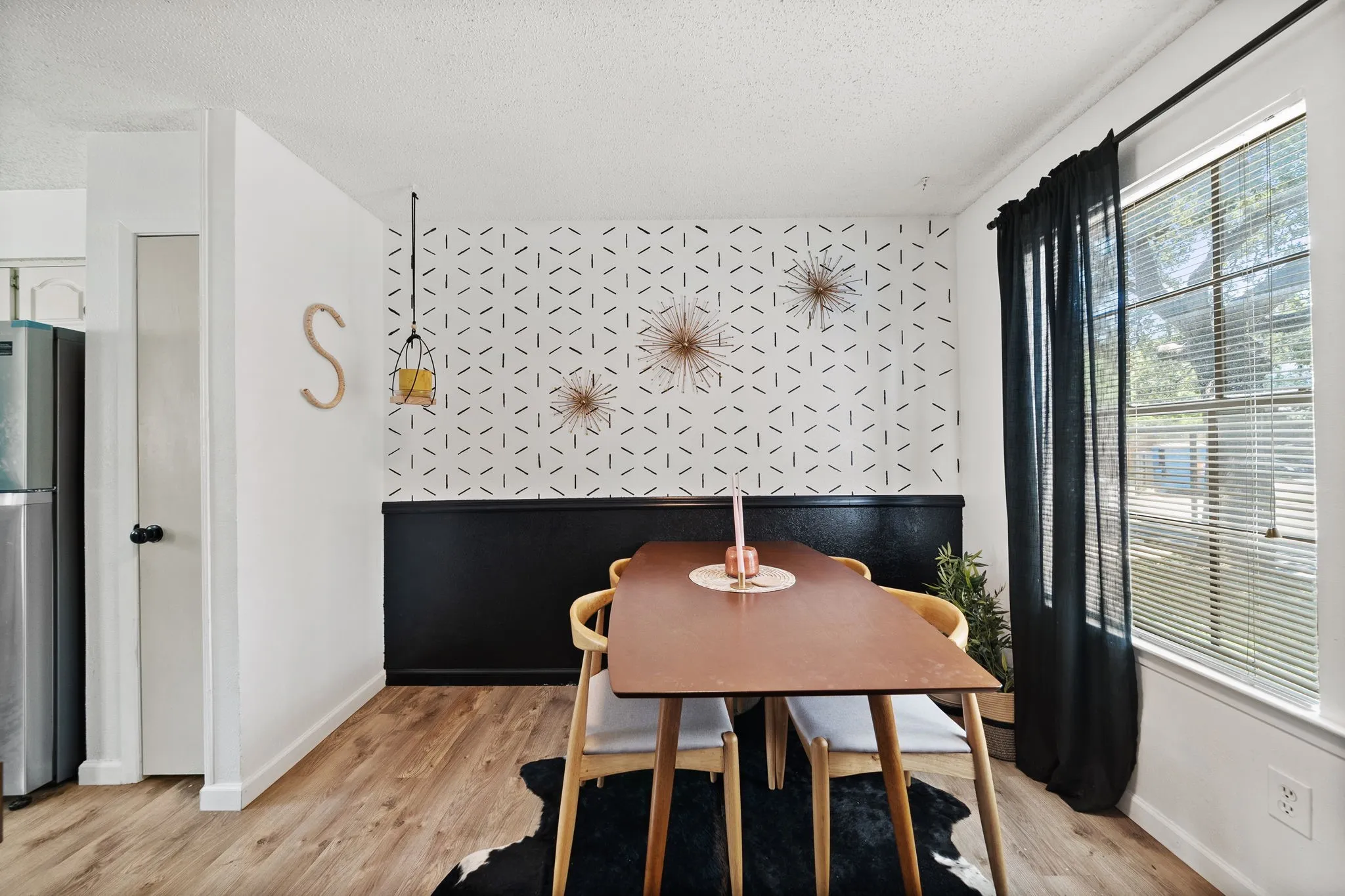 Dining space featuring wood-finish flooring, a two-toned wall treatment, and a window with blinds