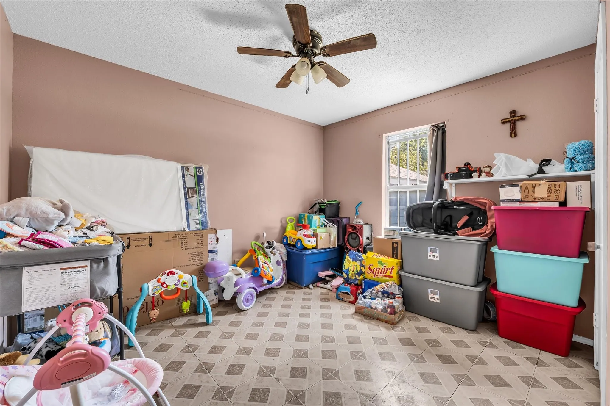 Room featuring patterned floor tile, a ceiling fan with integrated lighting, and a single window with security bars