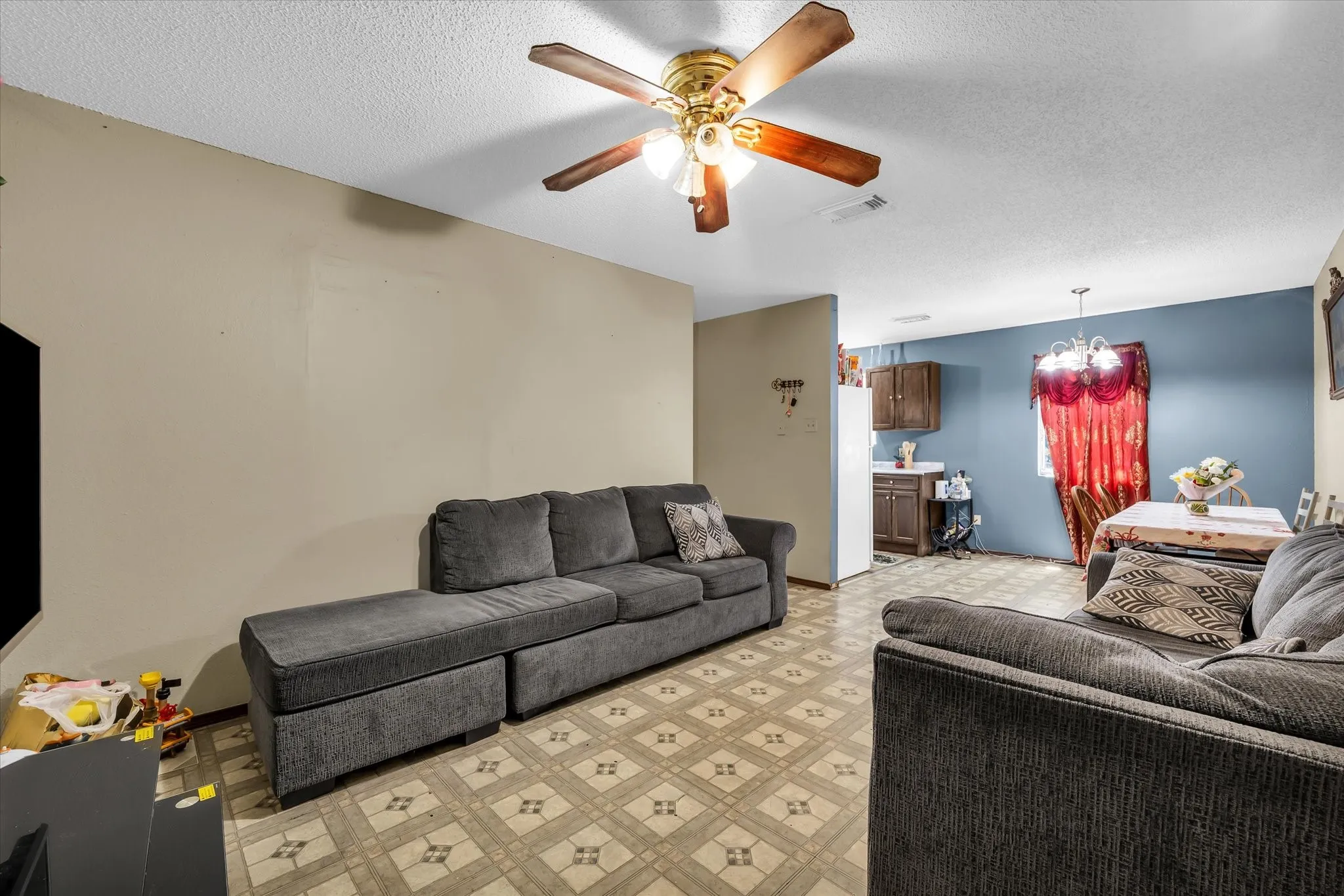 Open concept living area featuring patterned flooring, a ceiling fan with integrated lighting, and neutral wall tones