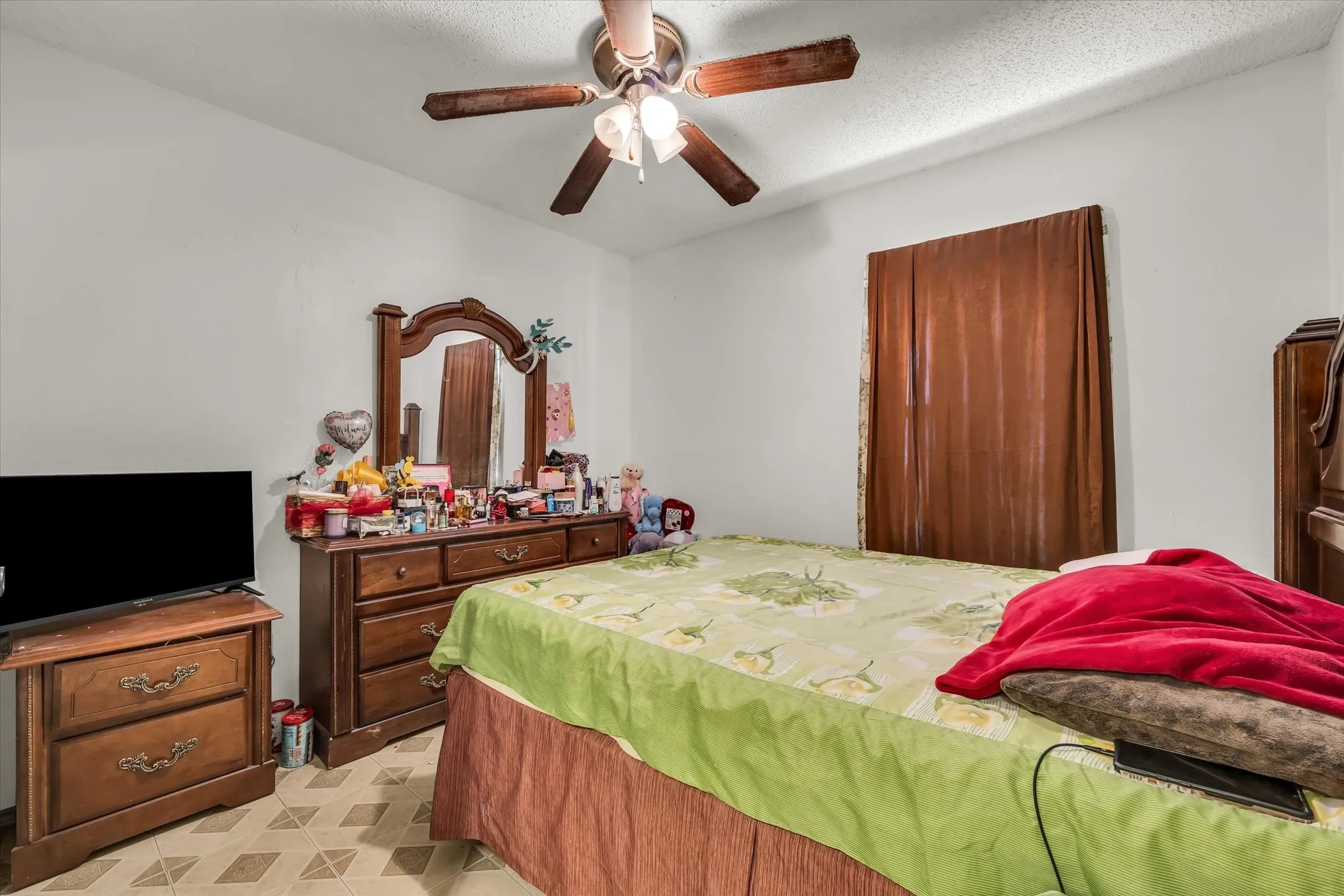 Interior room featuring a ceiling fan with light fixture, neutral wall color, and patterned floor tiles