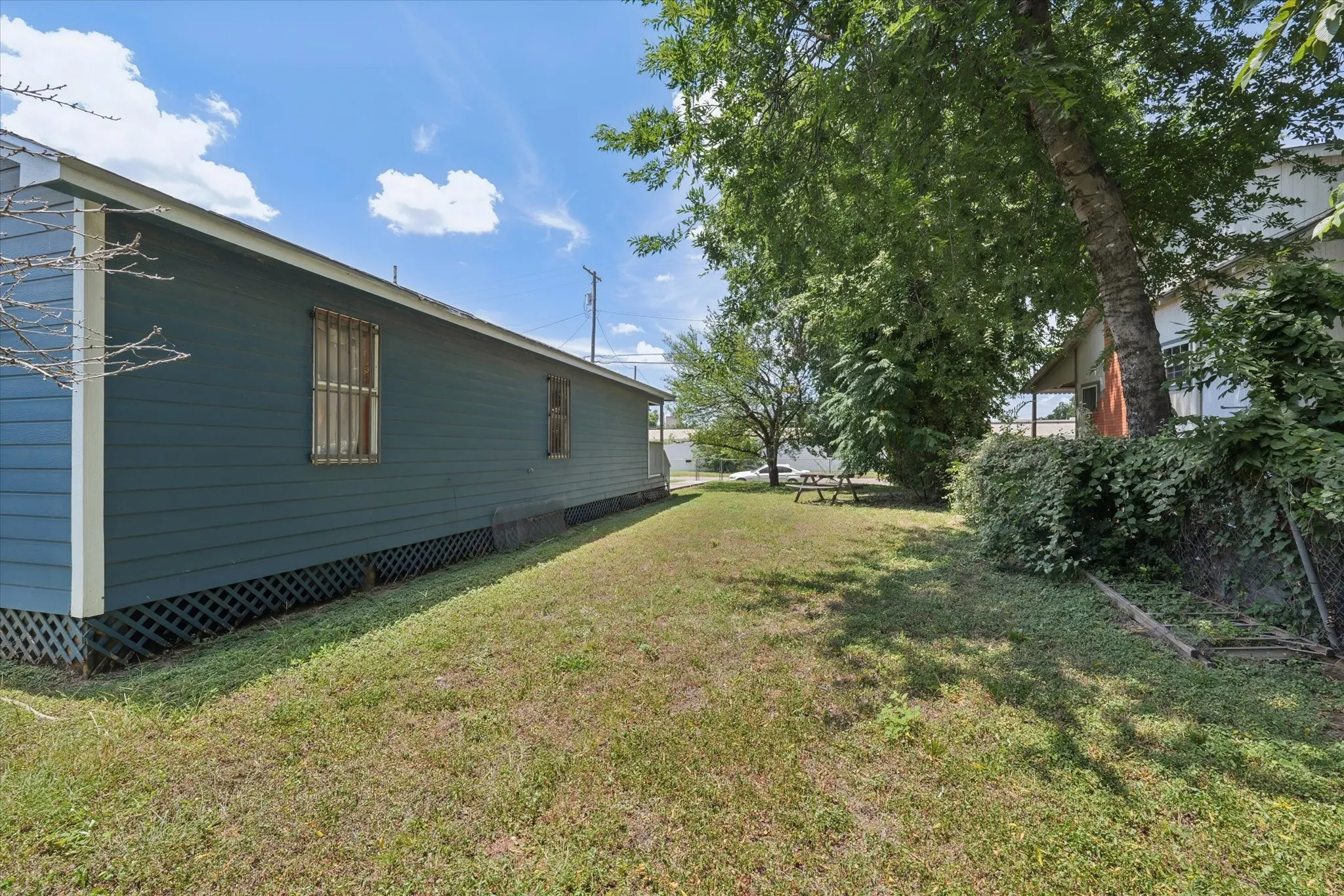 Expansive side yard featuring a well-maintained lawn and mature trees