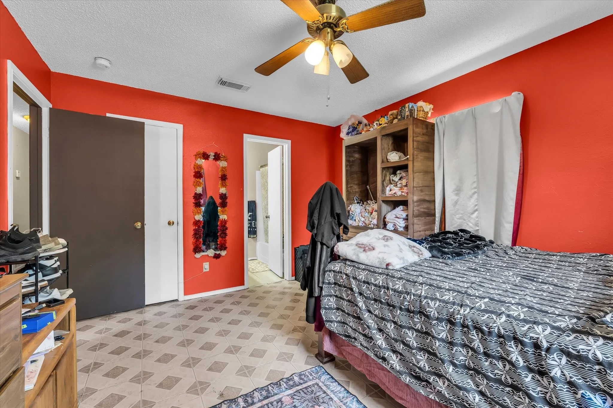 Bedroom featuring patterned tile flooring, a ceiling fan with light fixture, and vibrant wall color