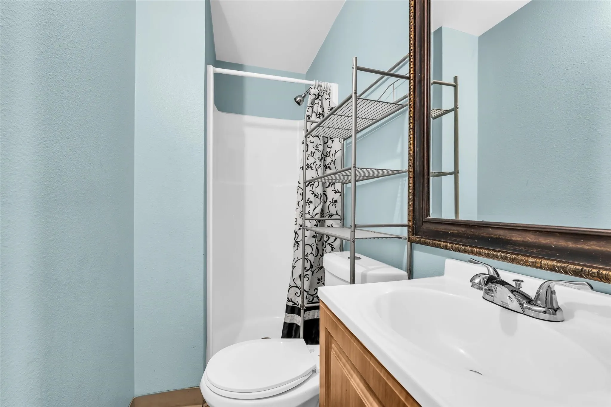 Bathroom featuring a white shower stall, a white toilet, and a wood-finish vanity with an integrated sink and chrome faucet