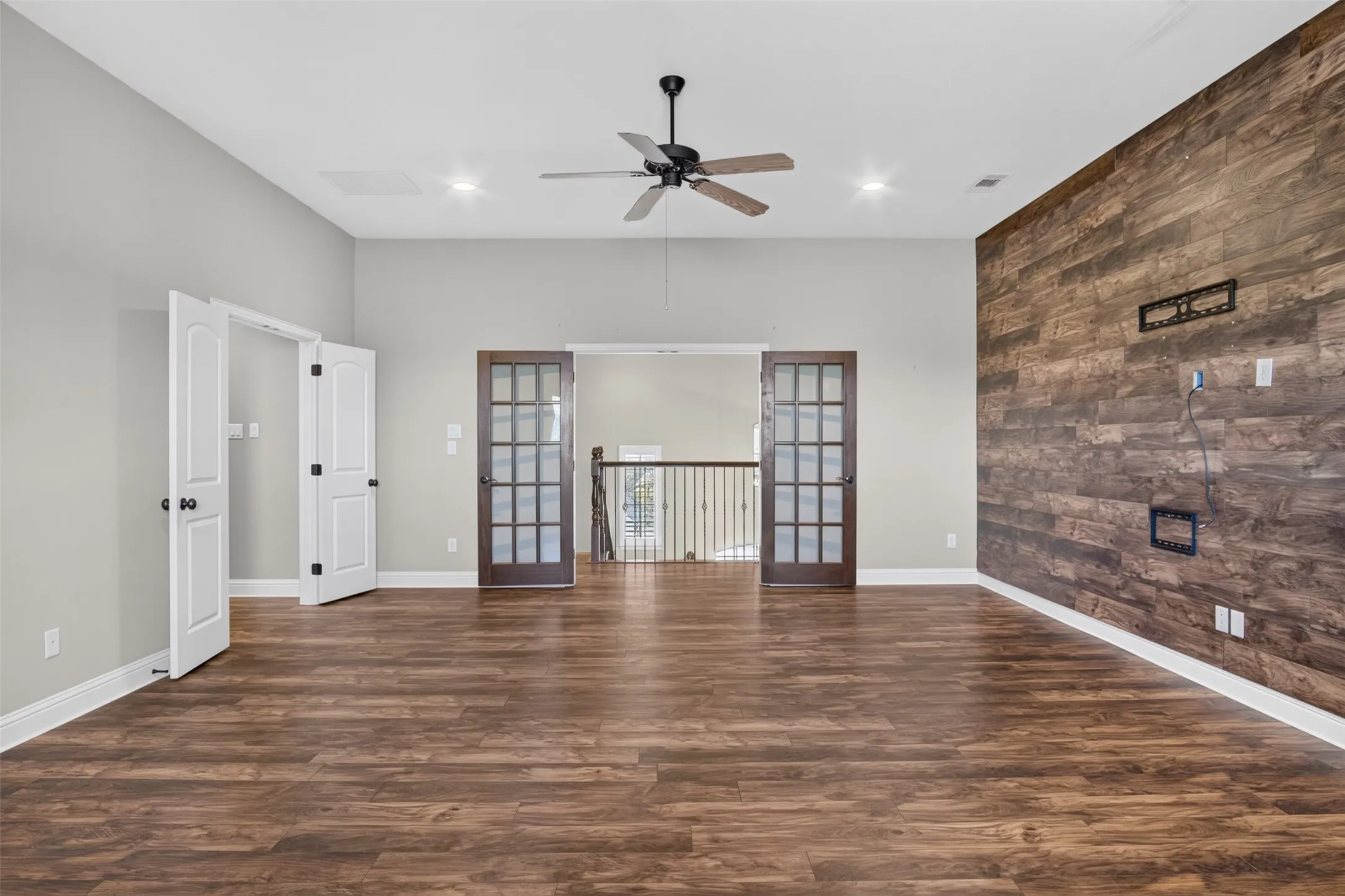 Wood-finish flooring throughout, featuring a distinctive wood accent wall and a ceiling fan with integrated lighting