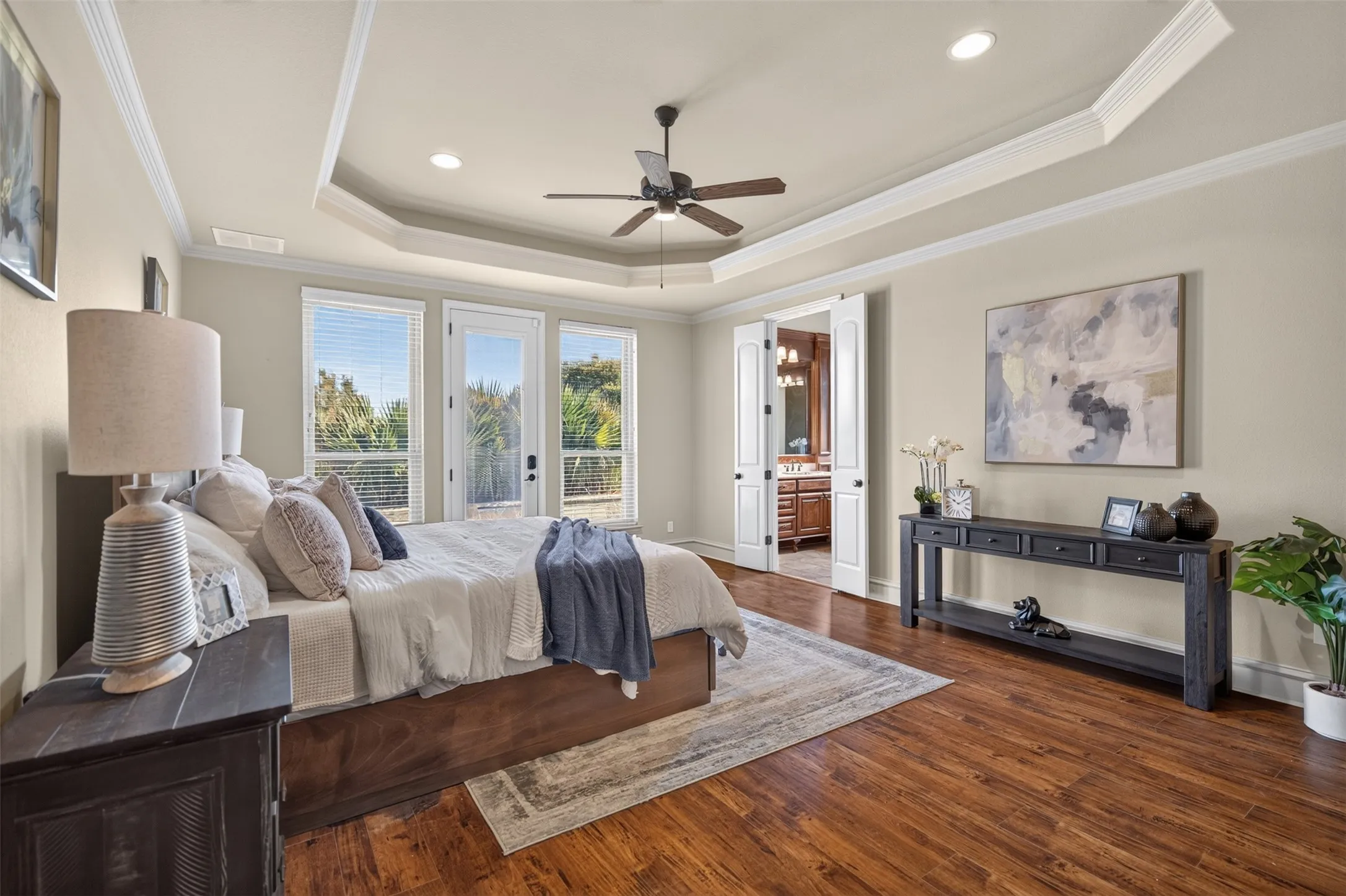 Tray ceiling with crown molding, recessed lighting, ceiling fan, and wood-finish flooring