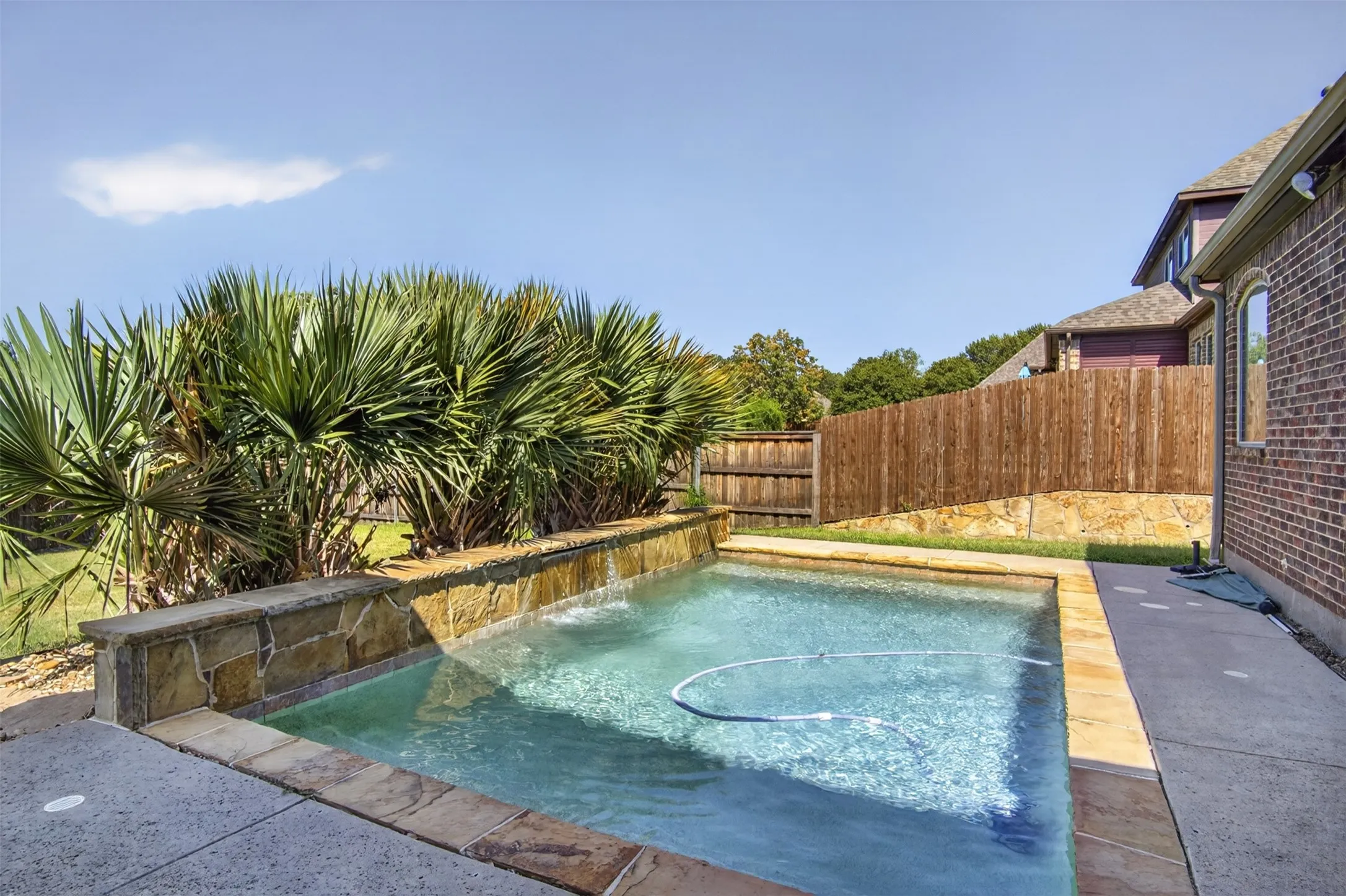 Private swimming pool with a stone-accented perimeter and water feature