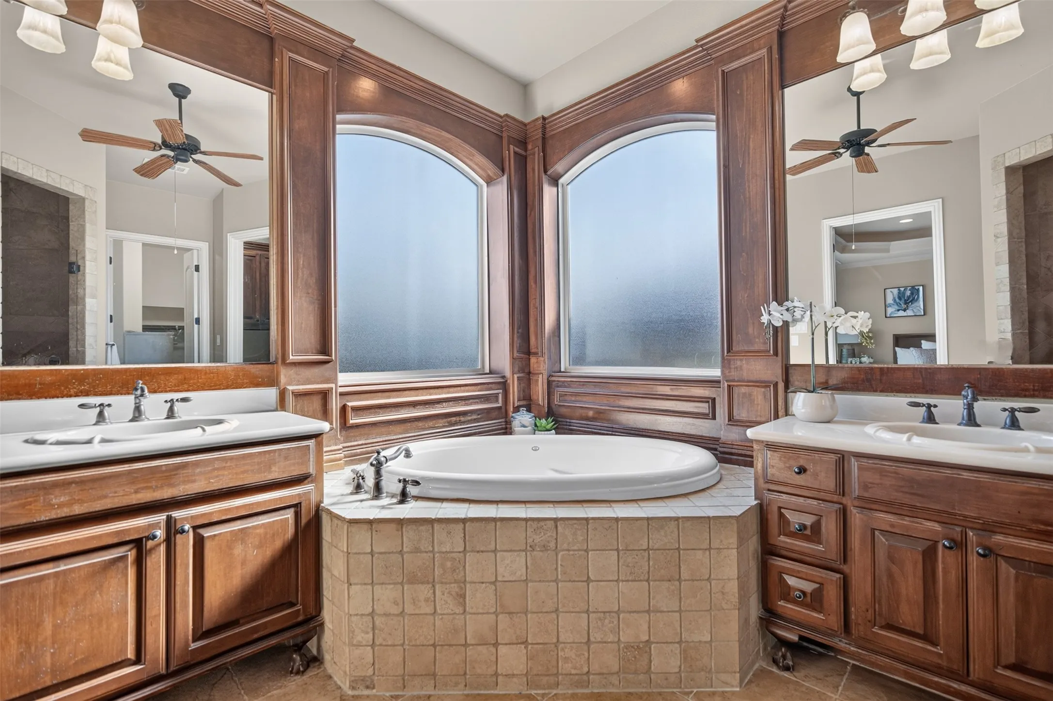 Built-in soaking tub with tile surround, flanked by two arched windows