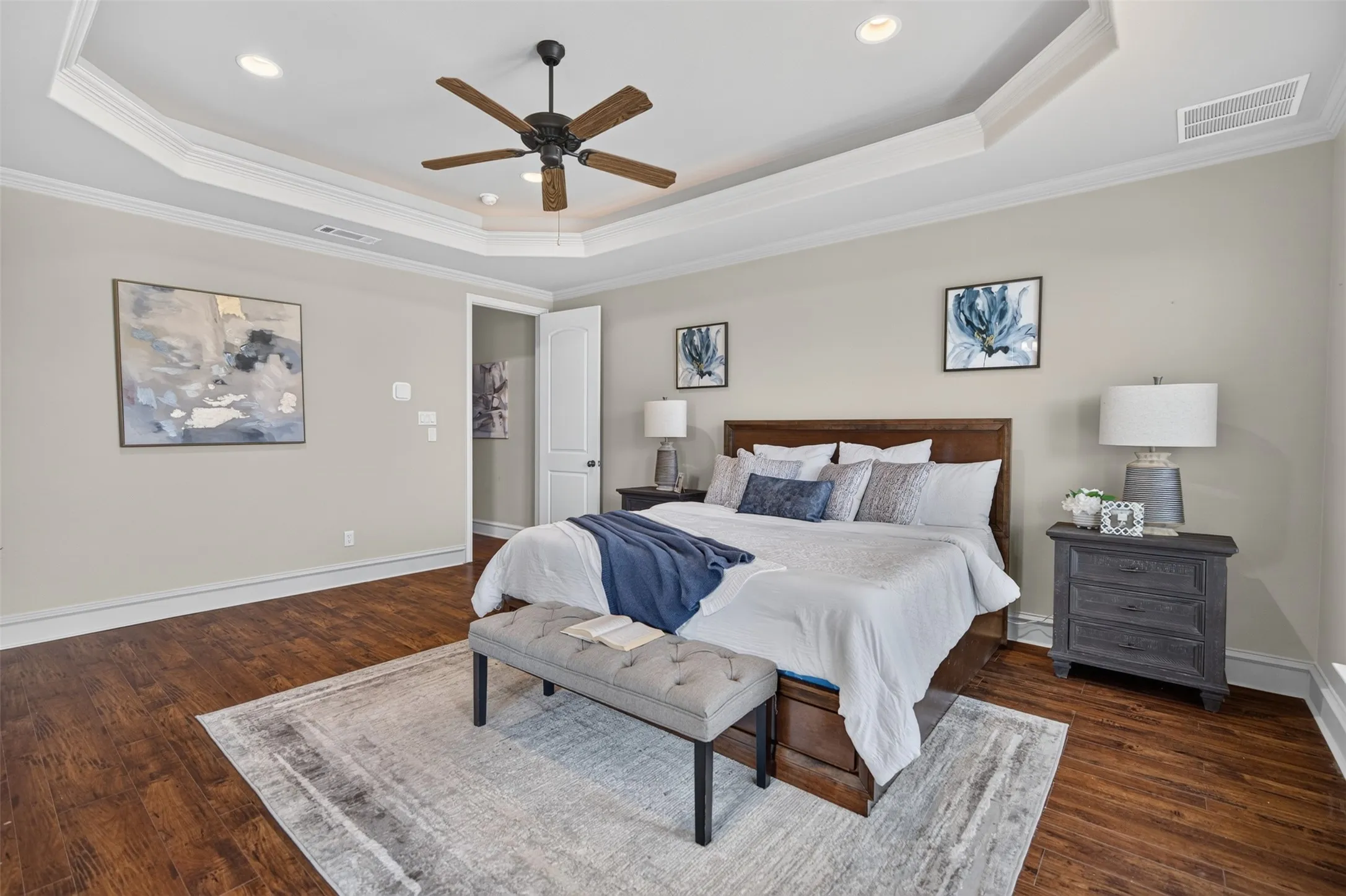 Tray ceiling with recessed lighting and a ceiling fan, wood-finish flooring, and a solid-core door