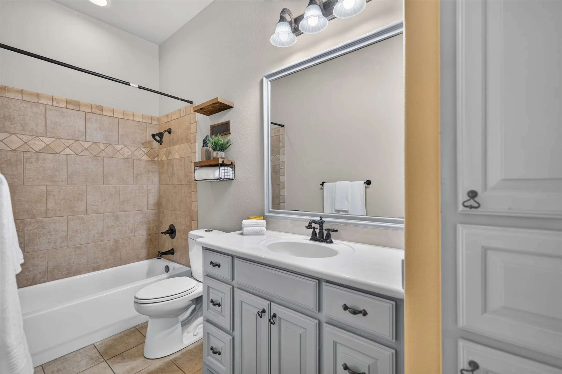 Bathroom featuring a tub/shower combination with tile surround, a vanity with a countertop and undermount sink, and a framed mirror with overhead lighting