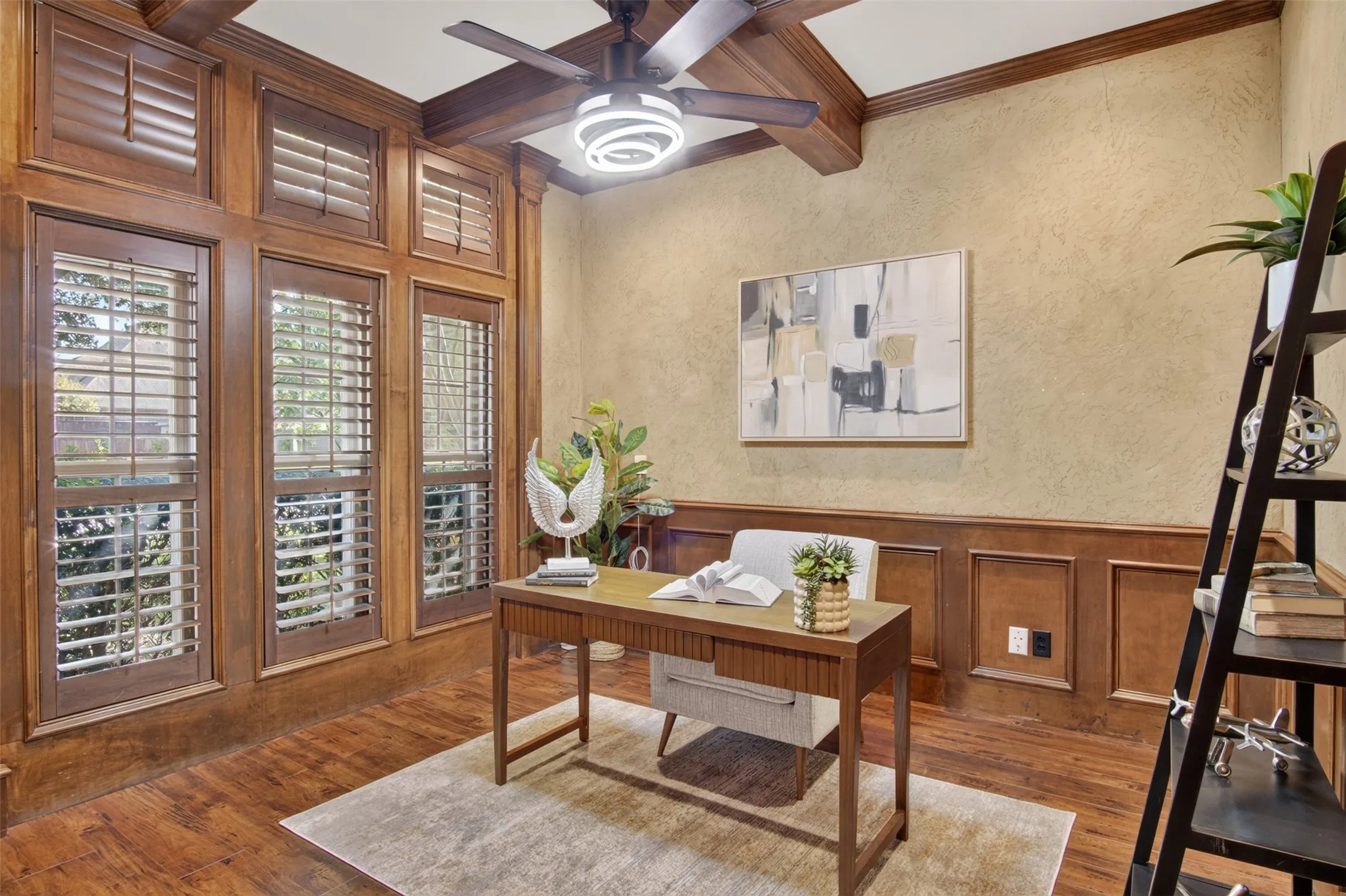 Wood-finish flooring, wood paneling, wood-framed windows with plantation shutters, wood ceiling beams, and a ceiling fan with integrated lighting
