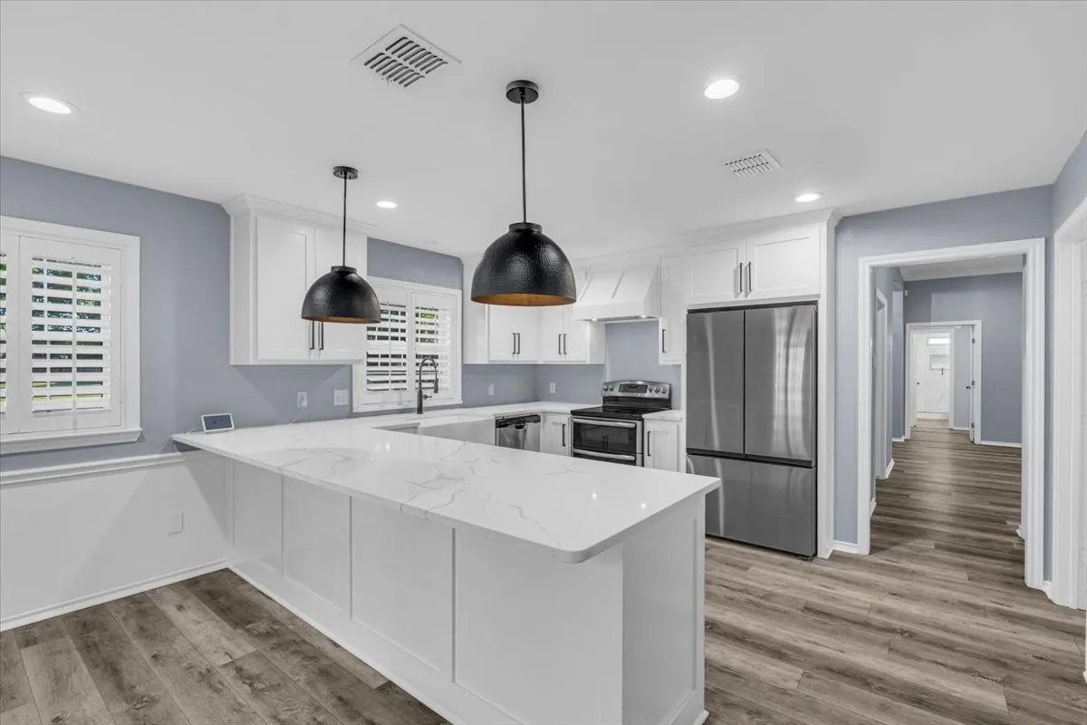 A stunning kitchen designed for both function and style, featuring an expansive quartz island, sleek stainless steel appliances, and elegant pendant lighting that perfectly complements the modern cabinetry.