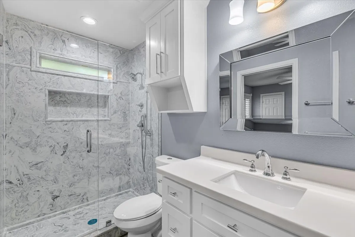 This tastefully updated powder room features a modern white vanity with a sleek quartz countertop, clean lines, and a minimalist aesthetic that complements the rest of the home's contemporary updates.