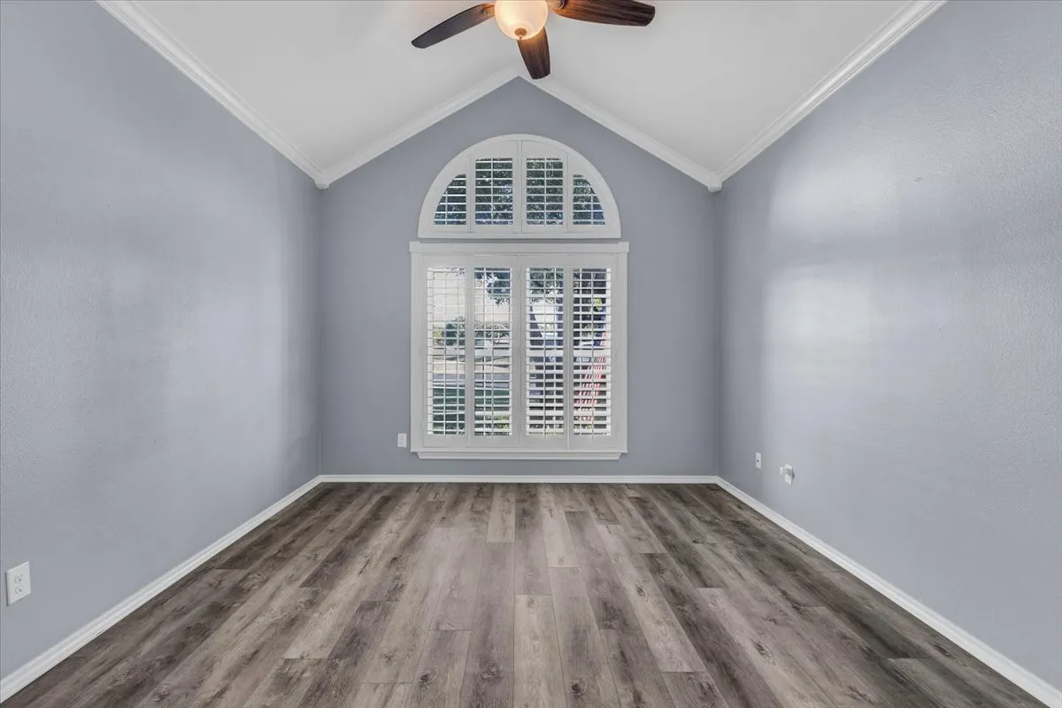 This stunning flex space or secondary living area is perfectly highlighted by a soaring vaulted ceiling and a massive, picturesque arched window dressed in beautiful custom plantation shutters.