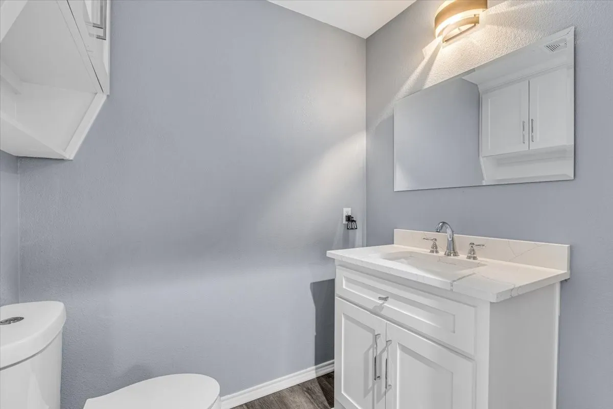 This tastefully updated half bath features a modern white vanity with a sleek quartz countertop, clean lines, and a minimalist aesthetic that complements the home's contemporary updates.