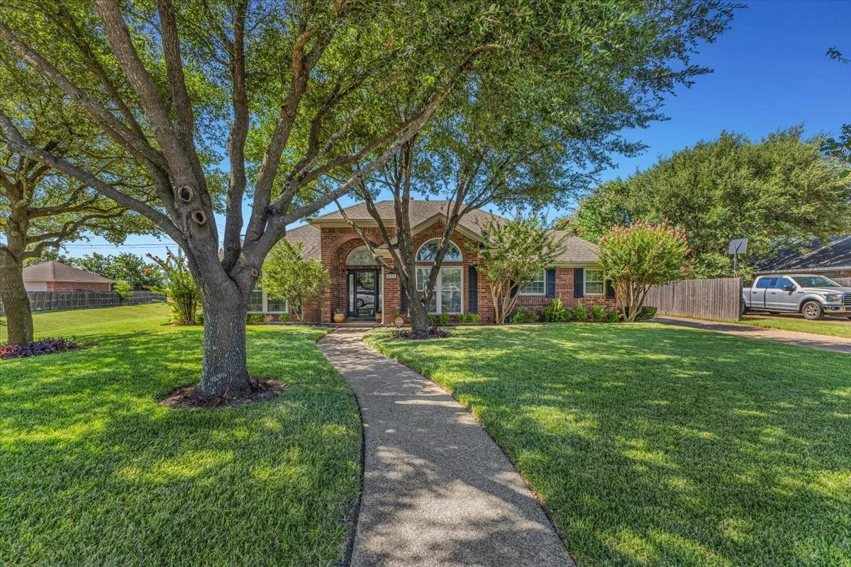 Exceptional curb appeal defines this stunning brick residence, featuring a grand arched entryway, meticulously landscaped grounds, and beautiful mature shade trees.