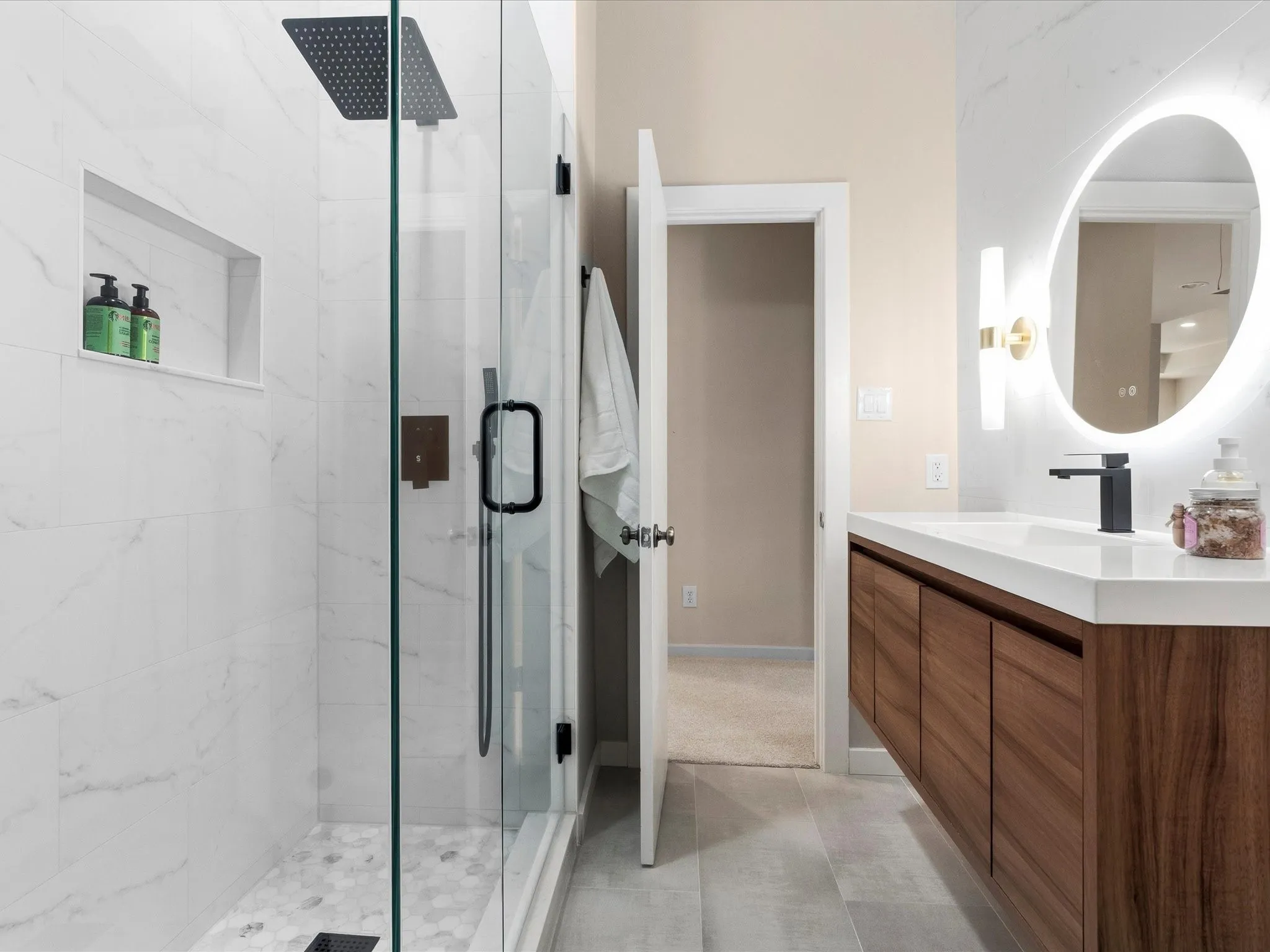 Contemporary Jack & Jill bathroom featuring a spacious glass-enclosed shower with a rainfall showerhead, white marble-look wall tiling, and a hexagon-tiled shower floor