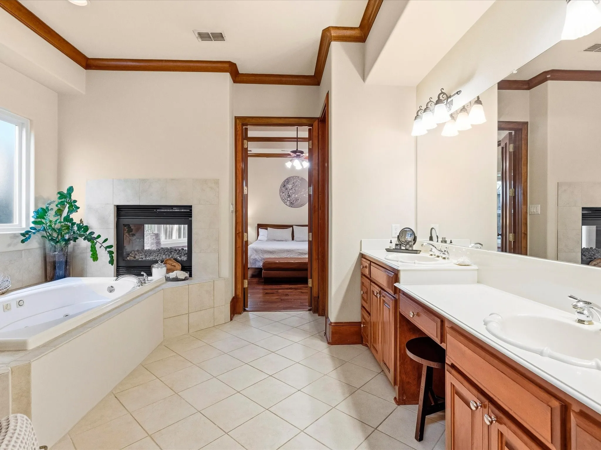 Spacious bathroom featuring a built-in jetted tub, fireplace with tile surround, and dual vanity with integrated sinks