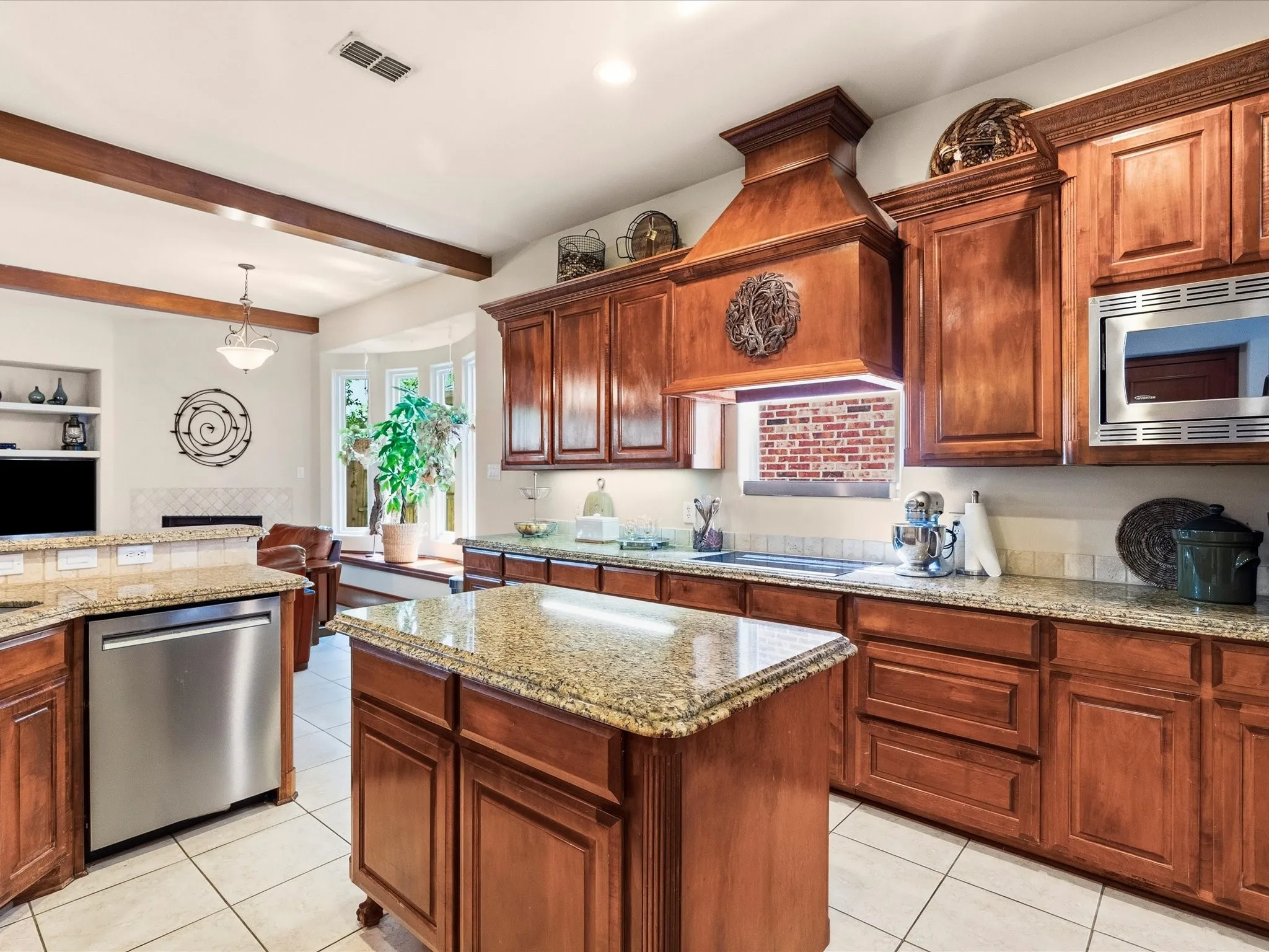 Spacious kitchen featuring rich wood cabinetry, granite countertops, stainless steel appliances, and a central island