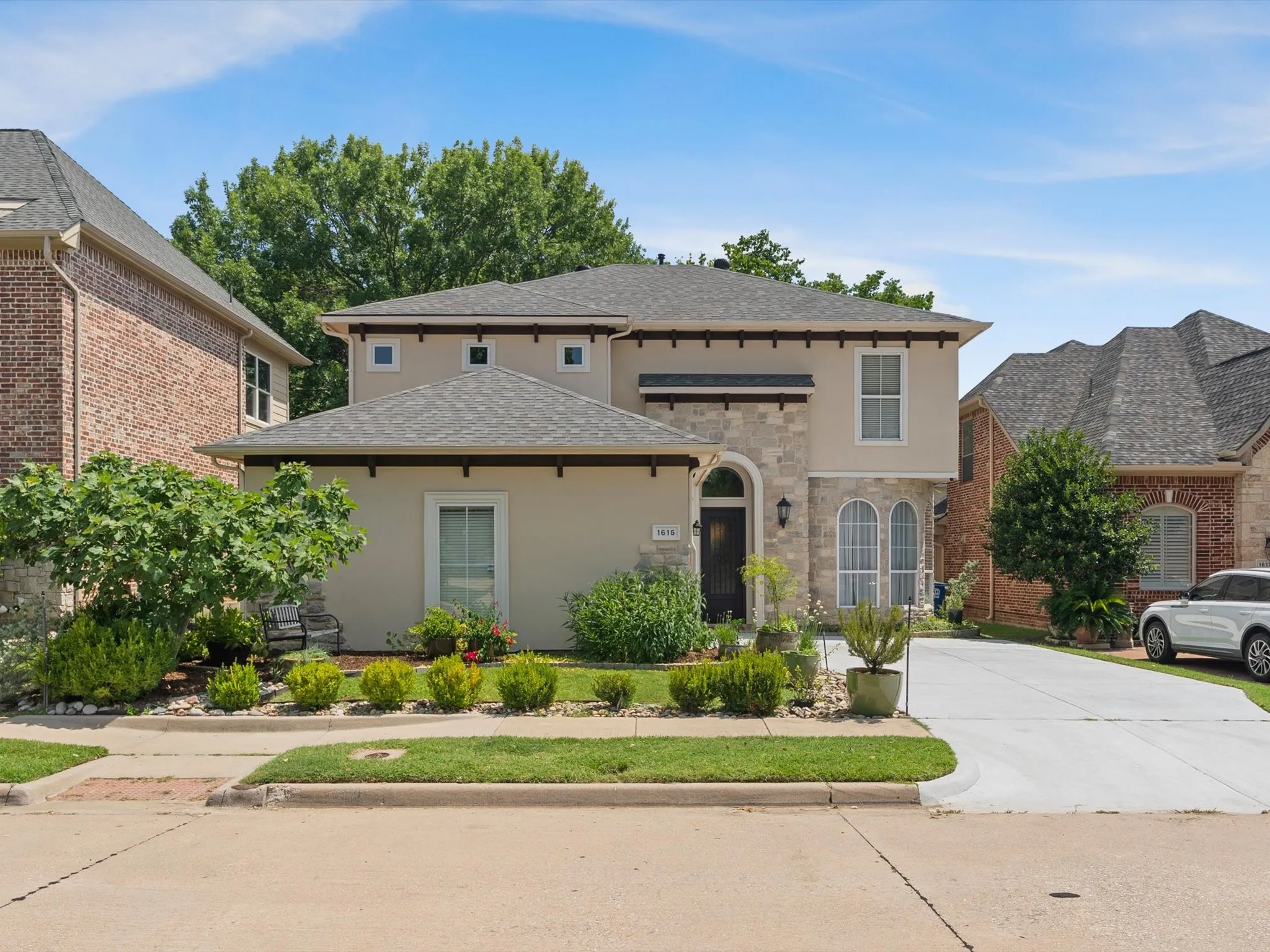 Stucco and stone facade with arched entry, complementing arched windows, and a concrete driveway